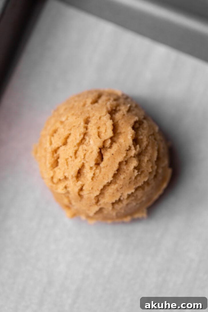 Spiced Apple Pie Cookies 8 Scooped cookie dough balls arranged on a parchment-lined baking sheet.