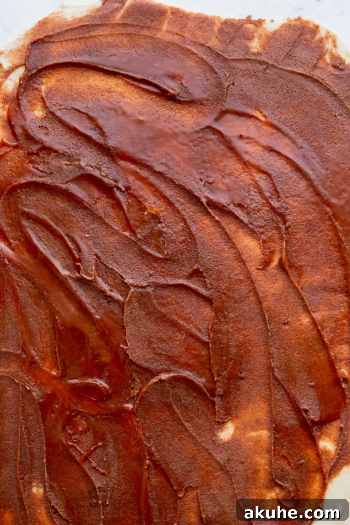 Decadent Caramel Cinnamon Rolls 11 Lush caramel drizzled over cinnamon filling on dough, ready to be rolled.