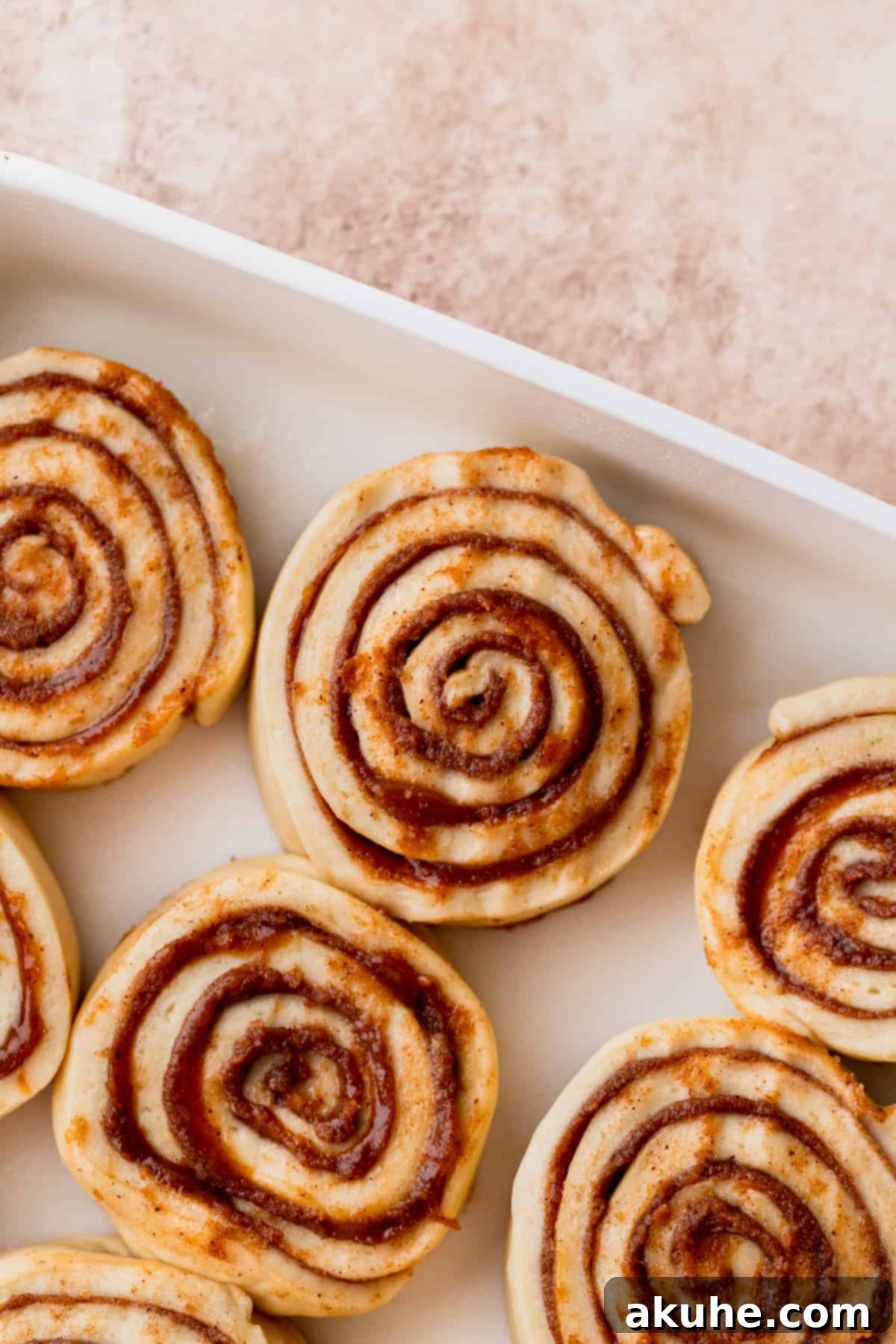 Decadent Caramel Cinnamon Rolls 12 Unbaked cinnamon rolls, perfectly sliced and arranged in a baking pan, ready for their final rise.