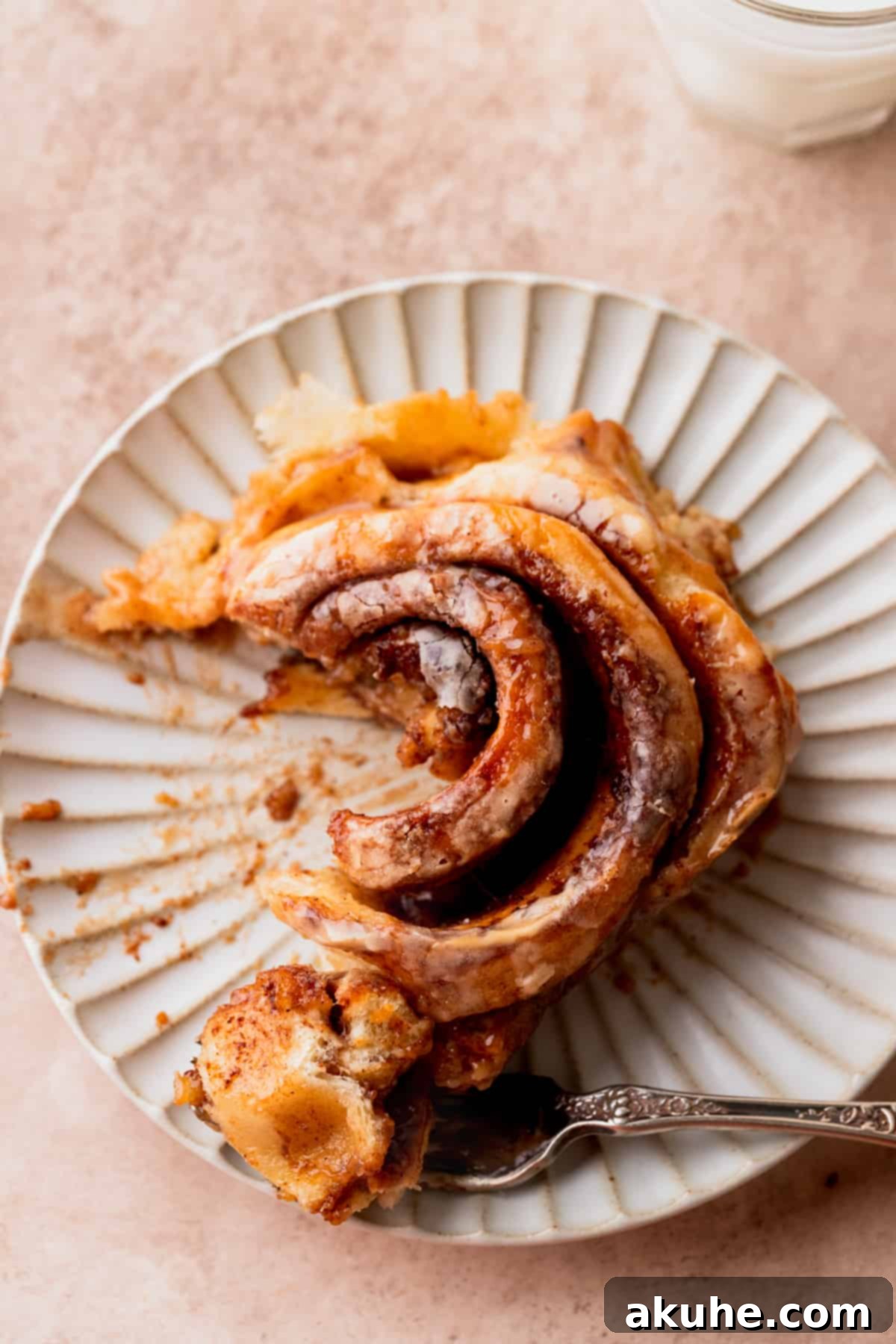 Decadent Caramel Cinnamon Rolls 16 Top-down view of a single caramel cinnamon roll on a white plate, showcasing its beautiful swirl and generous icing.