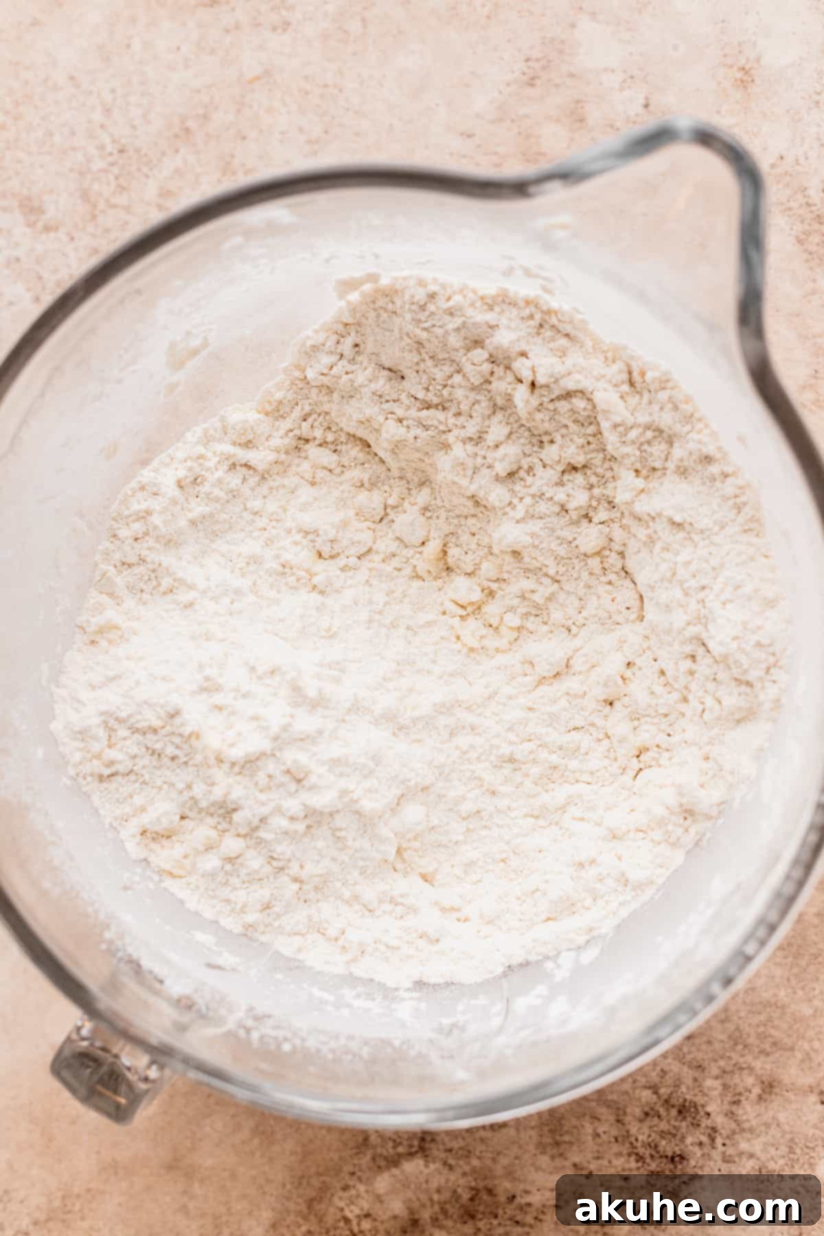 Decadent Caramel Cinnamon Rolls 4 Flour and butter in a clear glass bowl, showing the texture before mixing.