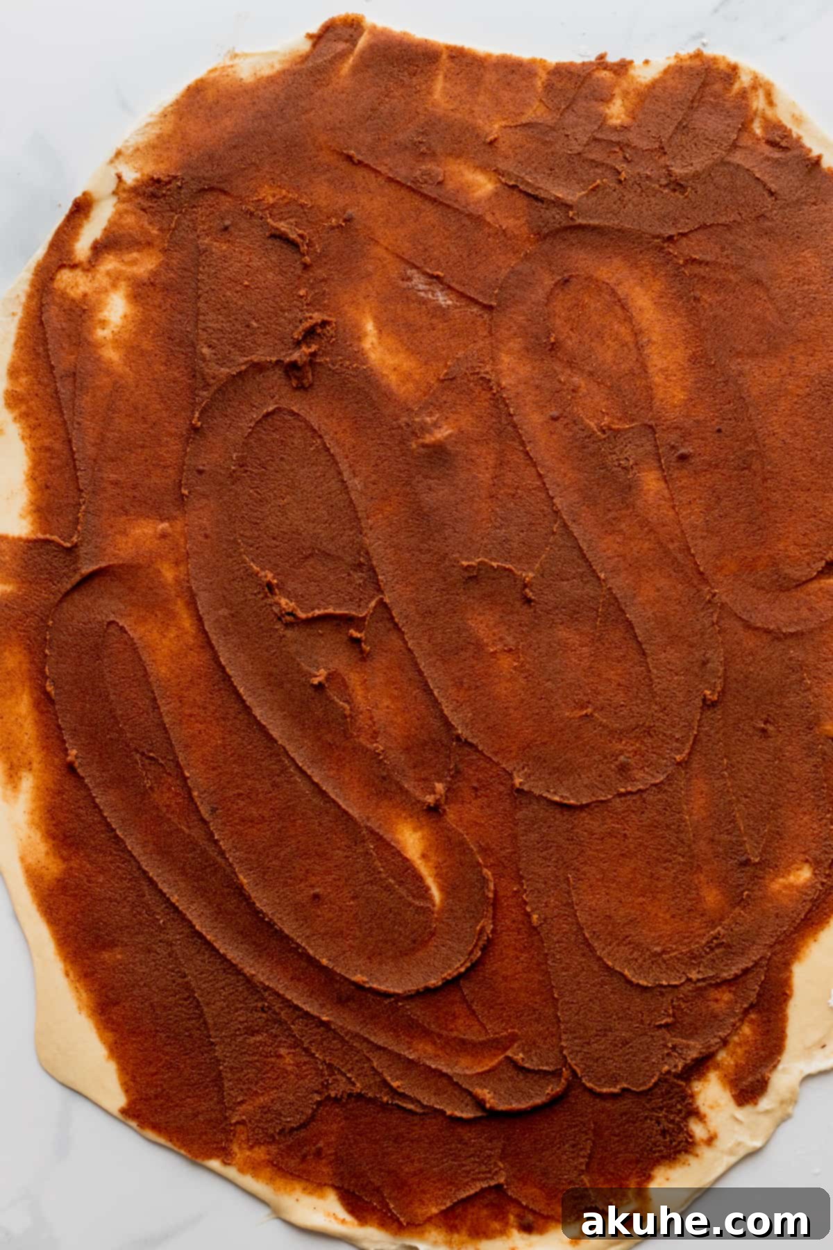 Decadent Caramel Cinnamon Rolls 10 Cinnamon filling generously spread on rolled-out dough, preparing for caramel drizzle.