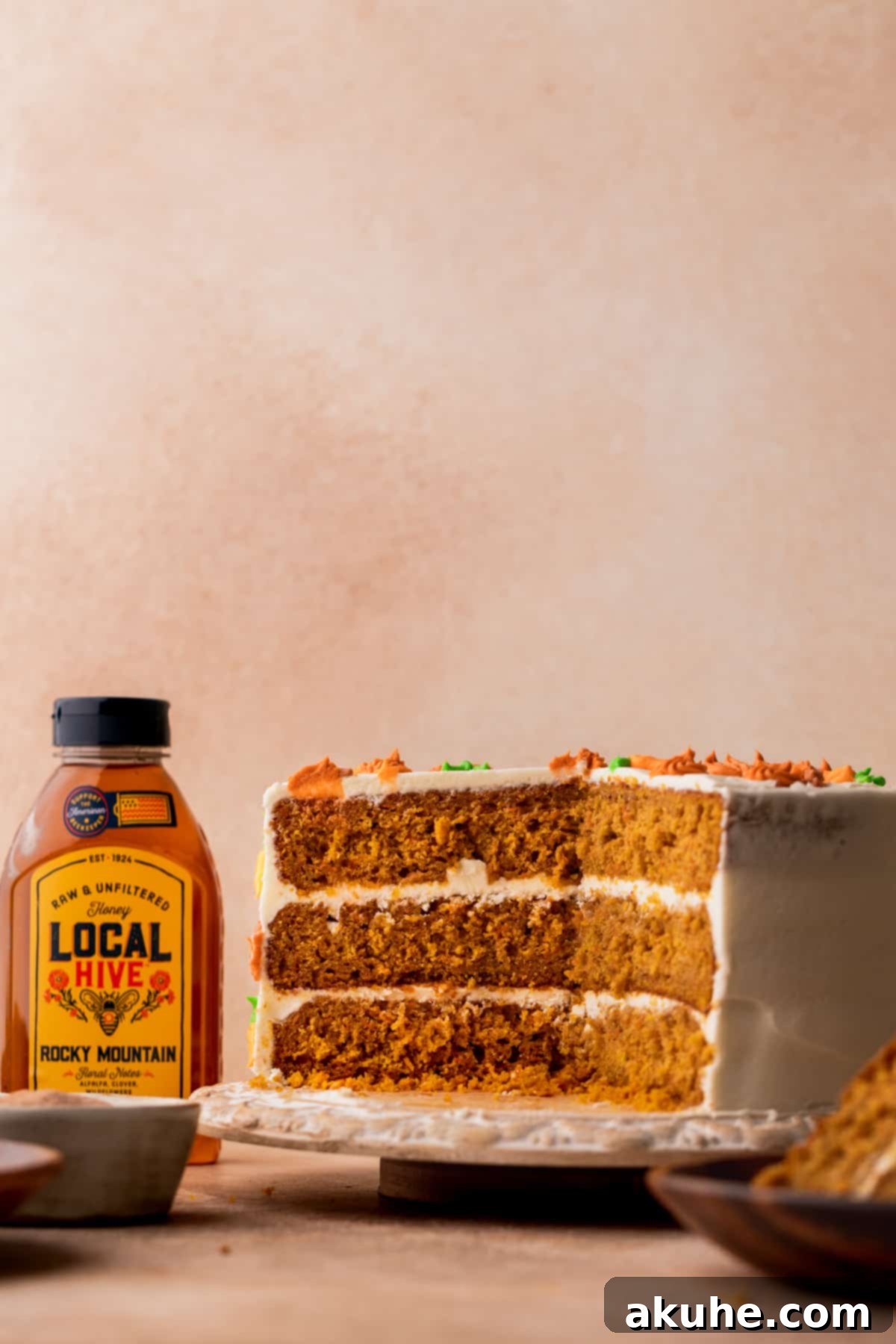 Pumpkin carrot cake cut in half, showcasing moist layers, rich frosting, and delicate decorations.