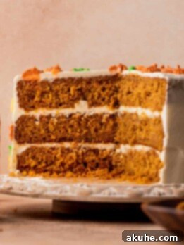 Pumpkin carrot cake cut in half, revealing moist layers and honey cream cheese frosting.