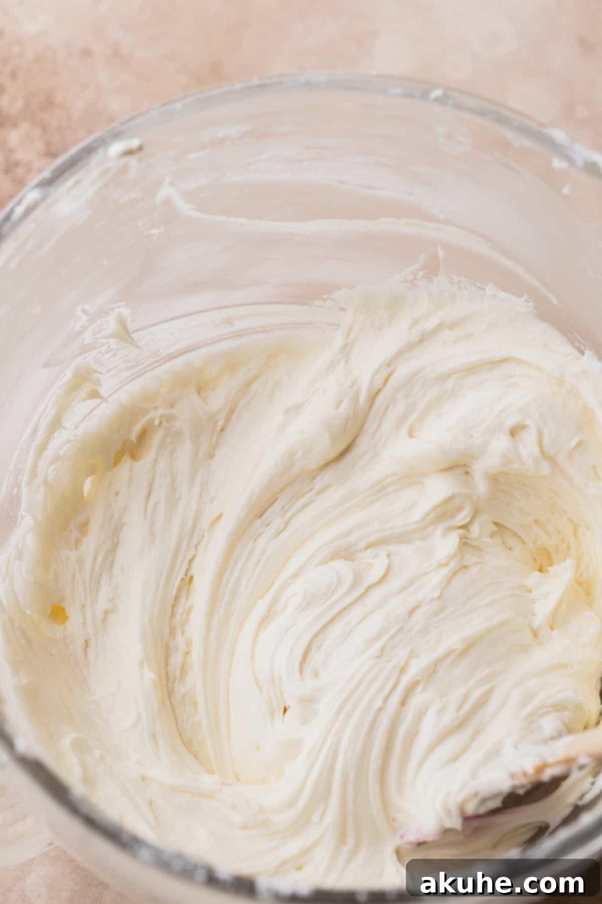 Fluffy cream cheese frosting in a glass bowl, perfectly whipped and ready.