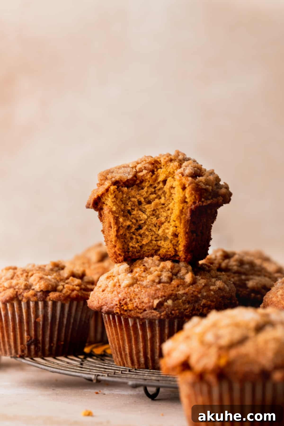Autumn Spiced Banana Pumpkin Muffins 3 A stack of two freshly baked pumpkin banana muffins on a wire cooling rack.