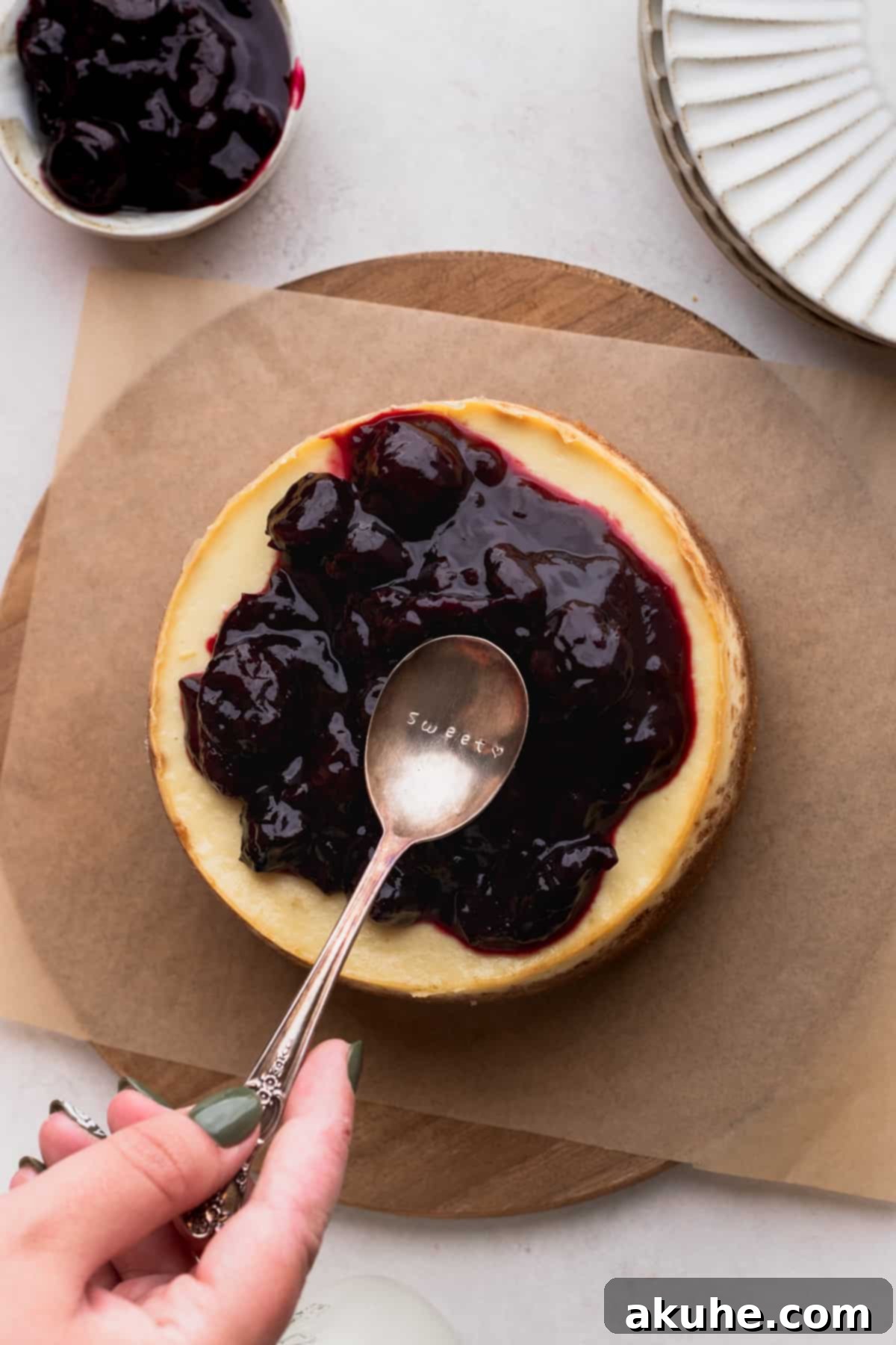 Mini Cheesecakes 11 Spreading a vibrant cherry topping evenly on top of a baked cheesecake.