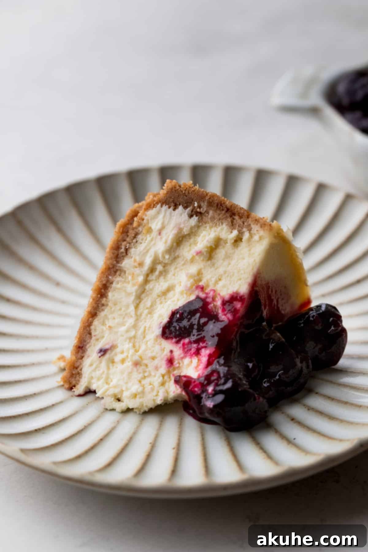 Mini Cheesecakes 3 One slice of small cheesecake on a plate, showcasing the cherry topping.