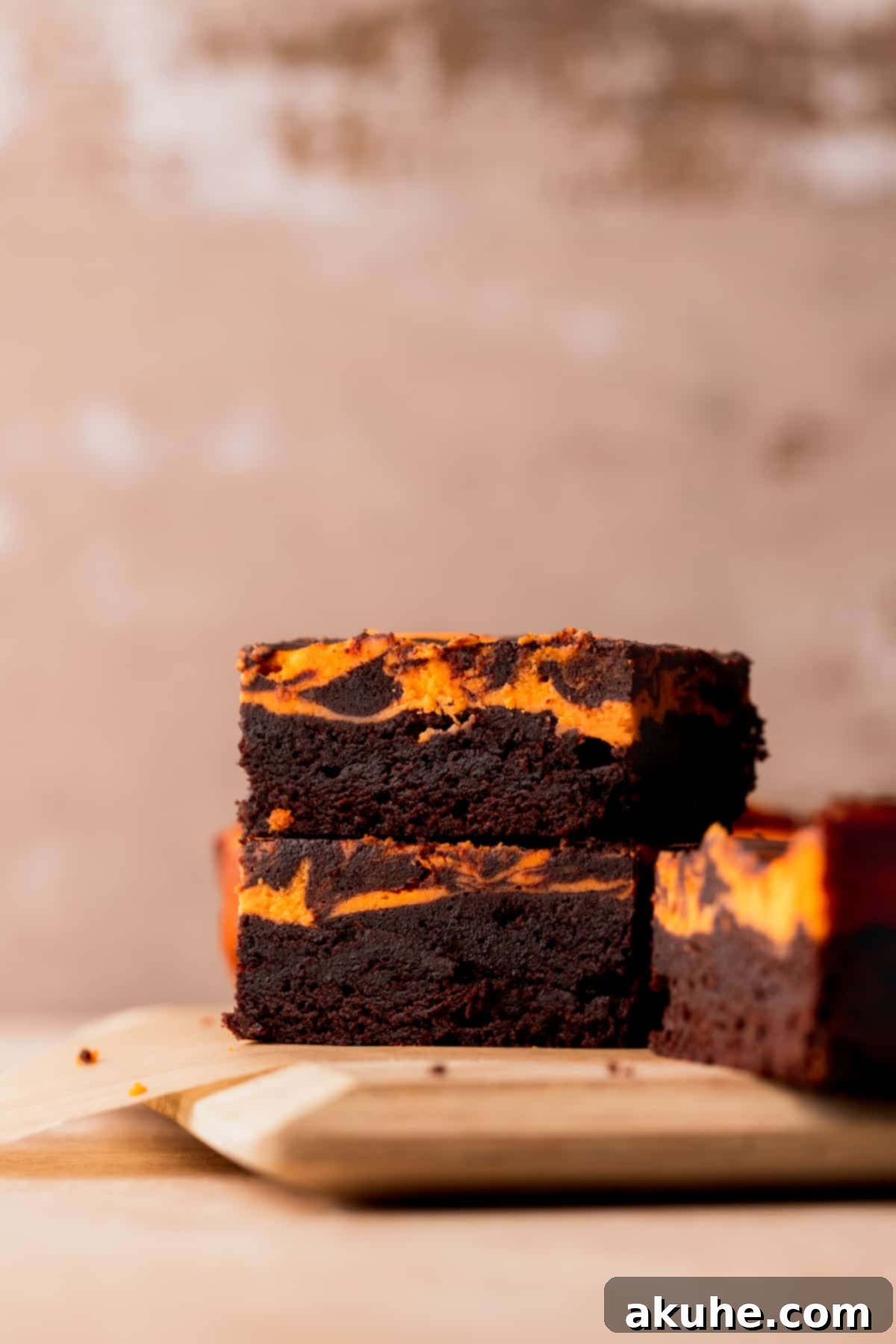 Stack of Halloween brownies, showcasing the fudgy layers and orange cheesecake swirl.