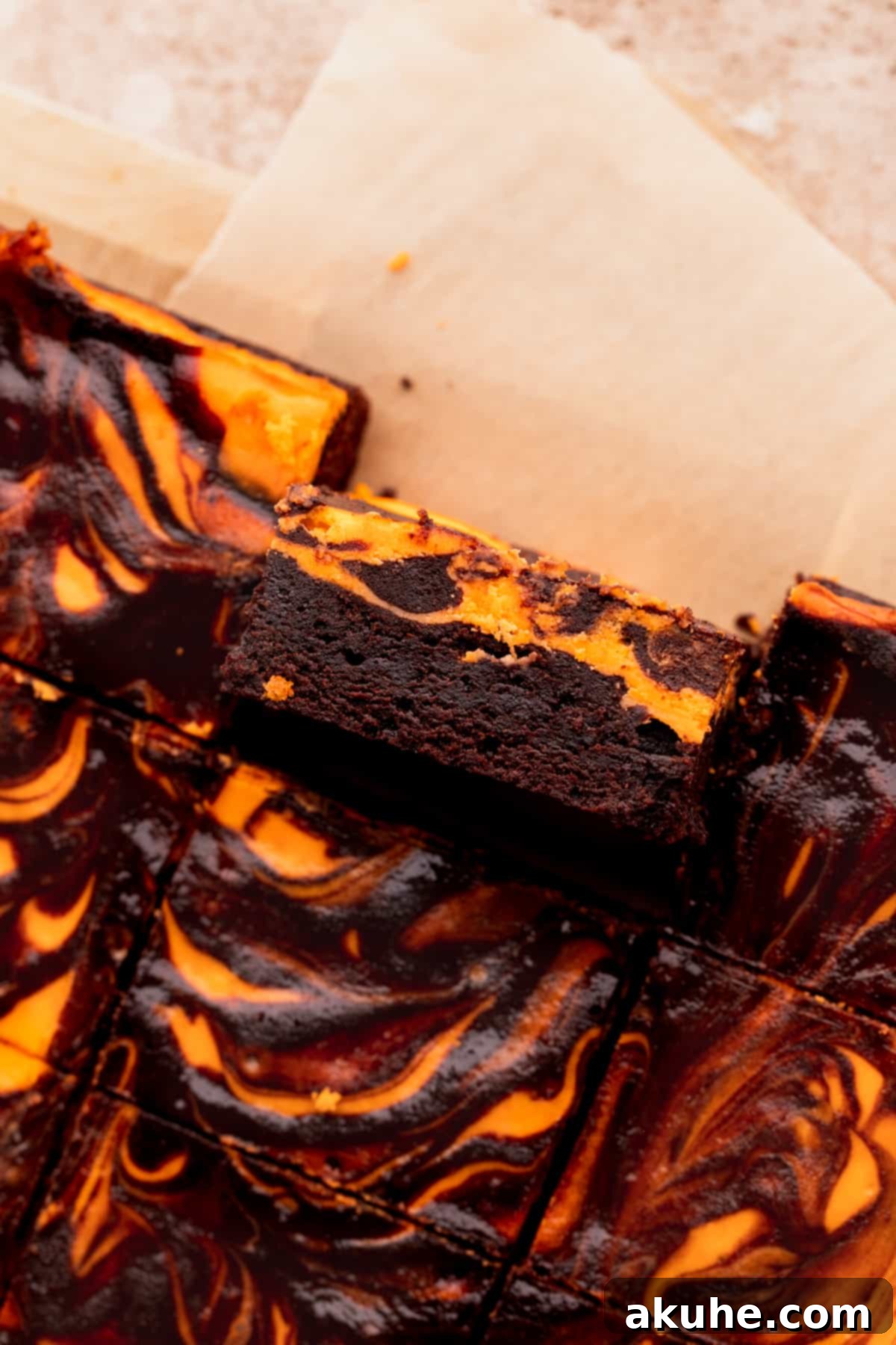 A single Halloween brownie on its side, revealing the distinct layers of chocolate and orange cheesecake.