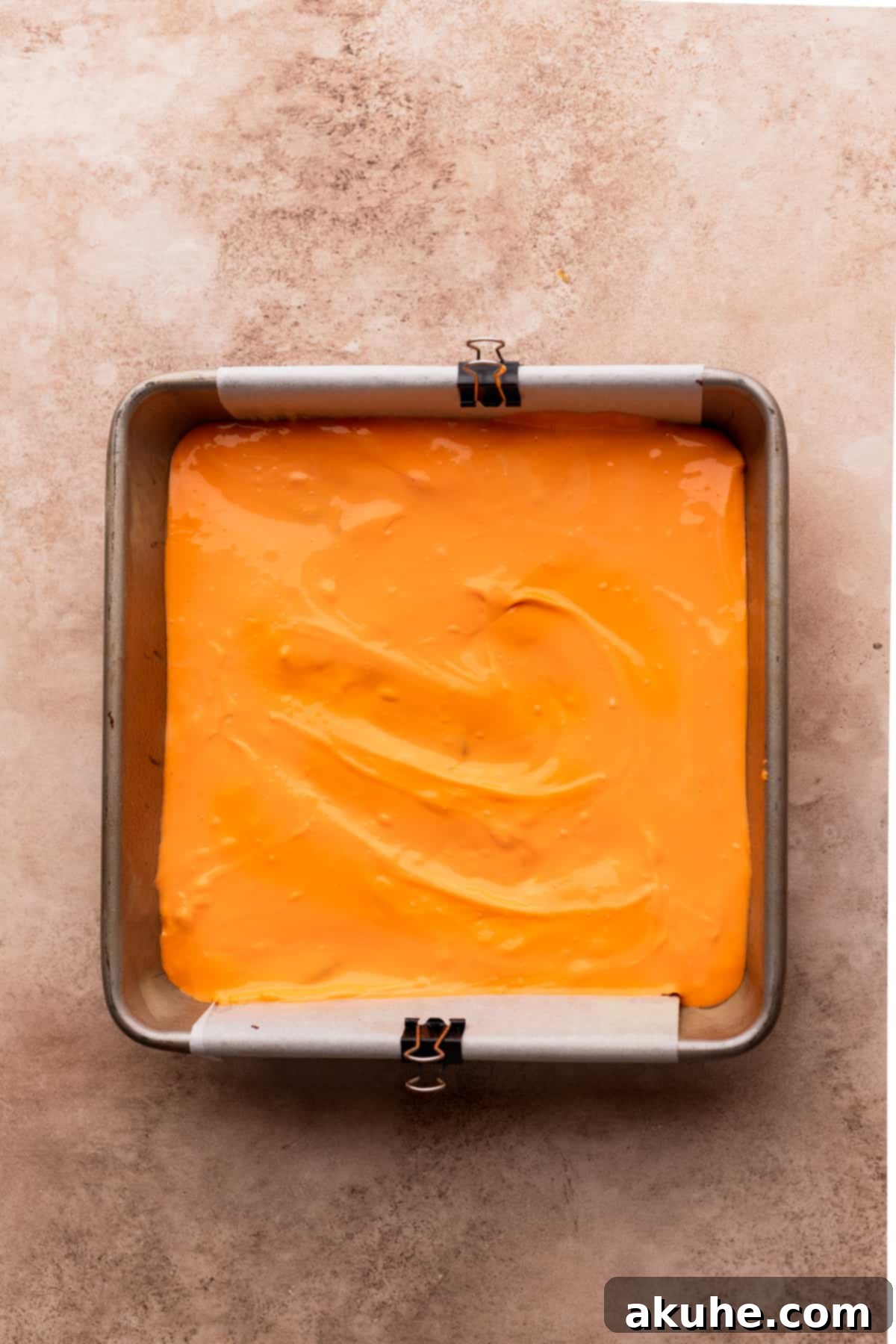 Orange cheesecake layer carefully spread on top of the brownie batter.