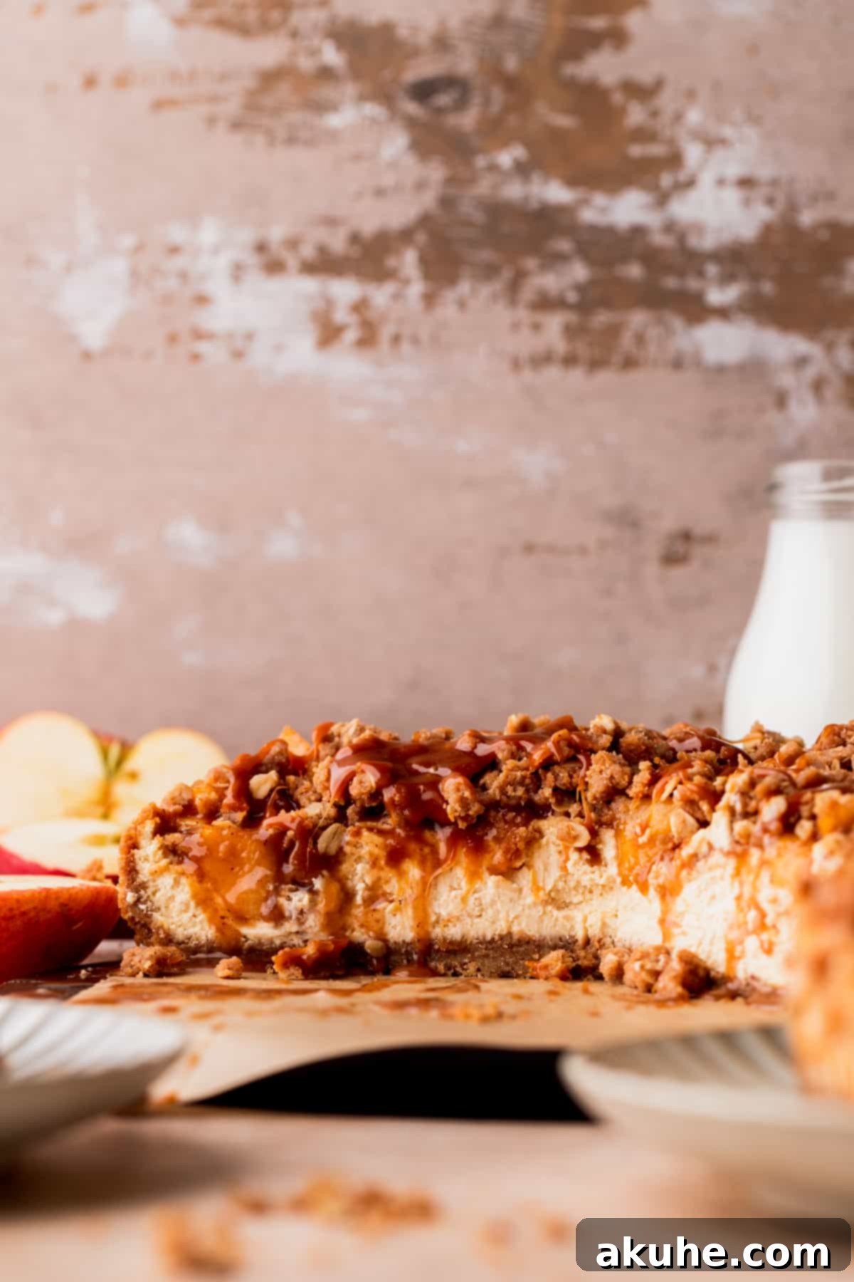Ultimate Apple Crumble Cheesecake 2 A beautifully sliced apple crumble cheesecake on a serving board, showcasing its distinct layers of crust, creamy filling, apple topping, and oat crumble.