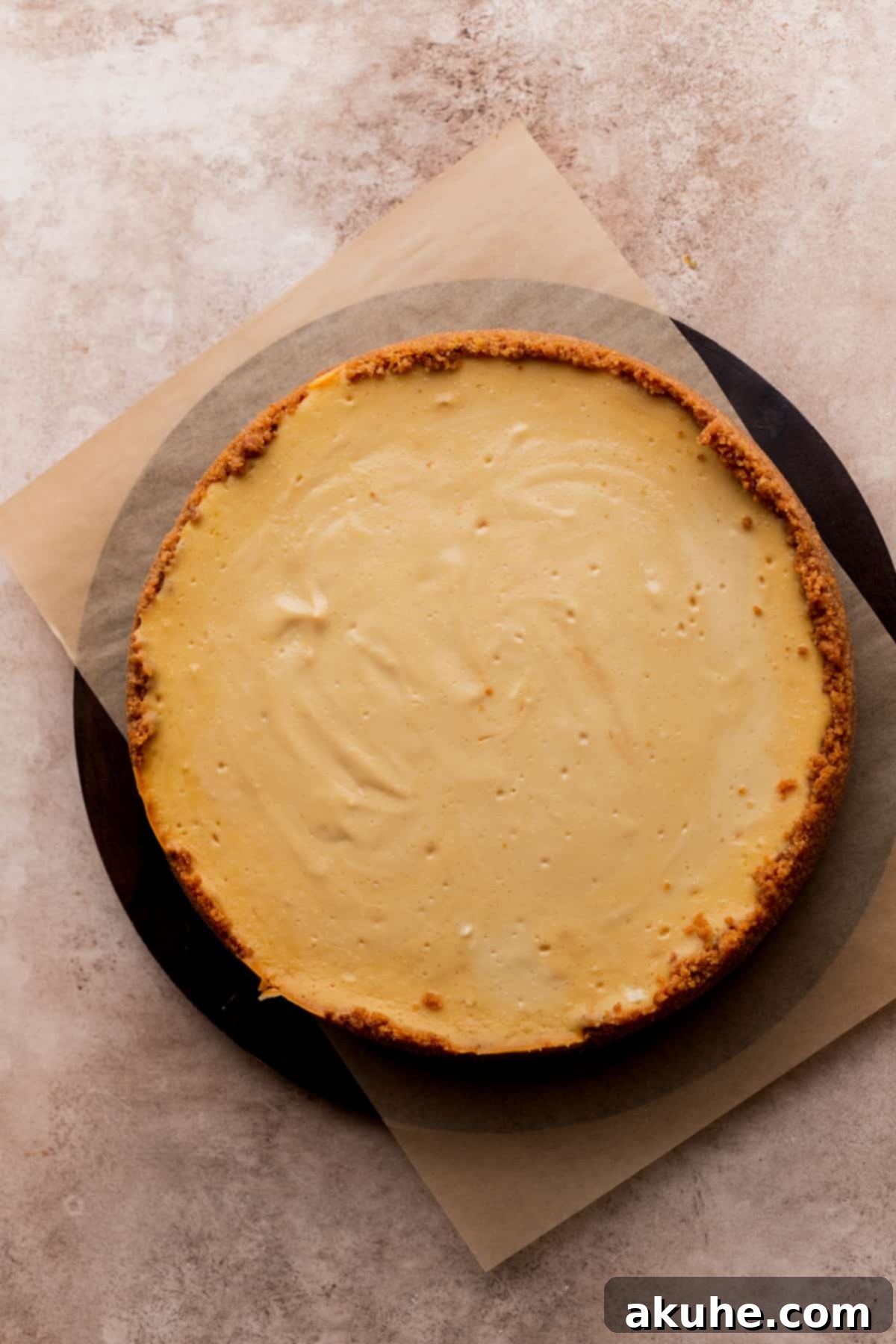 Ultimate Apple Crumble Cheesecake 11 A baked cheesecake removed from its springform pan, resting on a board.