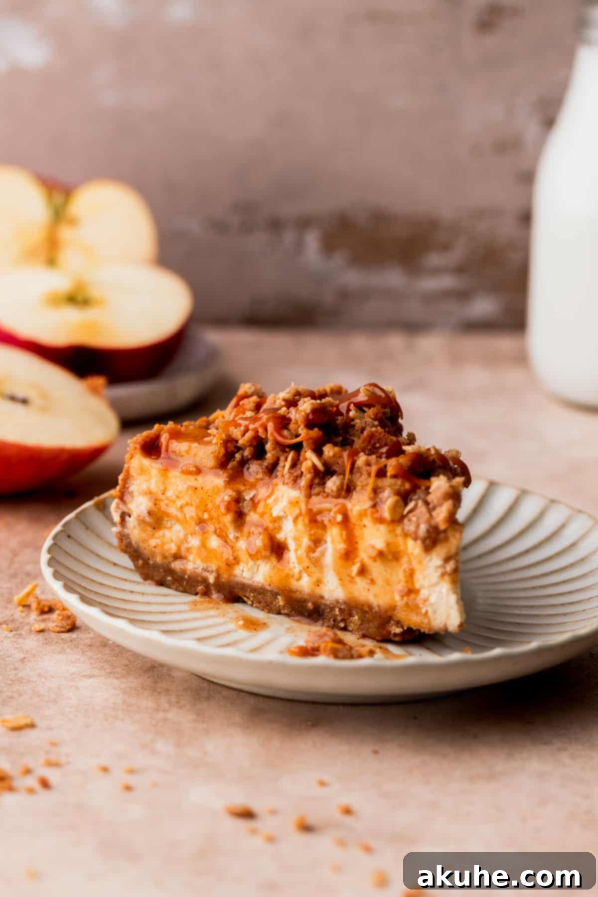 Ultimate Apple Crumble Cheesecake 15 A single, delectable slice of apple crumble cheesecake served on a white plate, showcasing its layers.