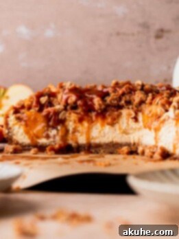 Ultimate Apple Crumble Cheesecake 16 Apple crumble cheesecake cut in half on a board.