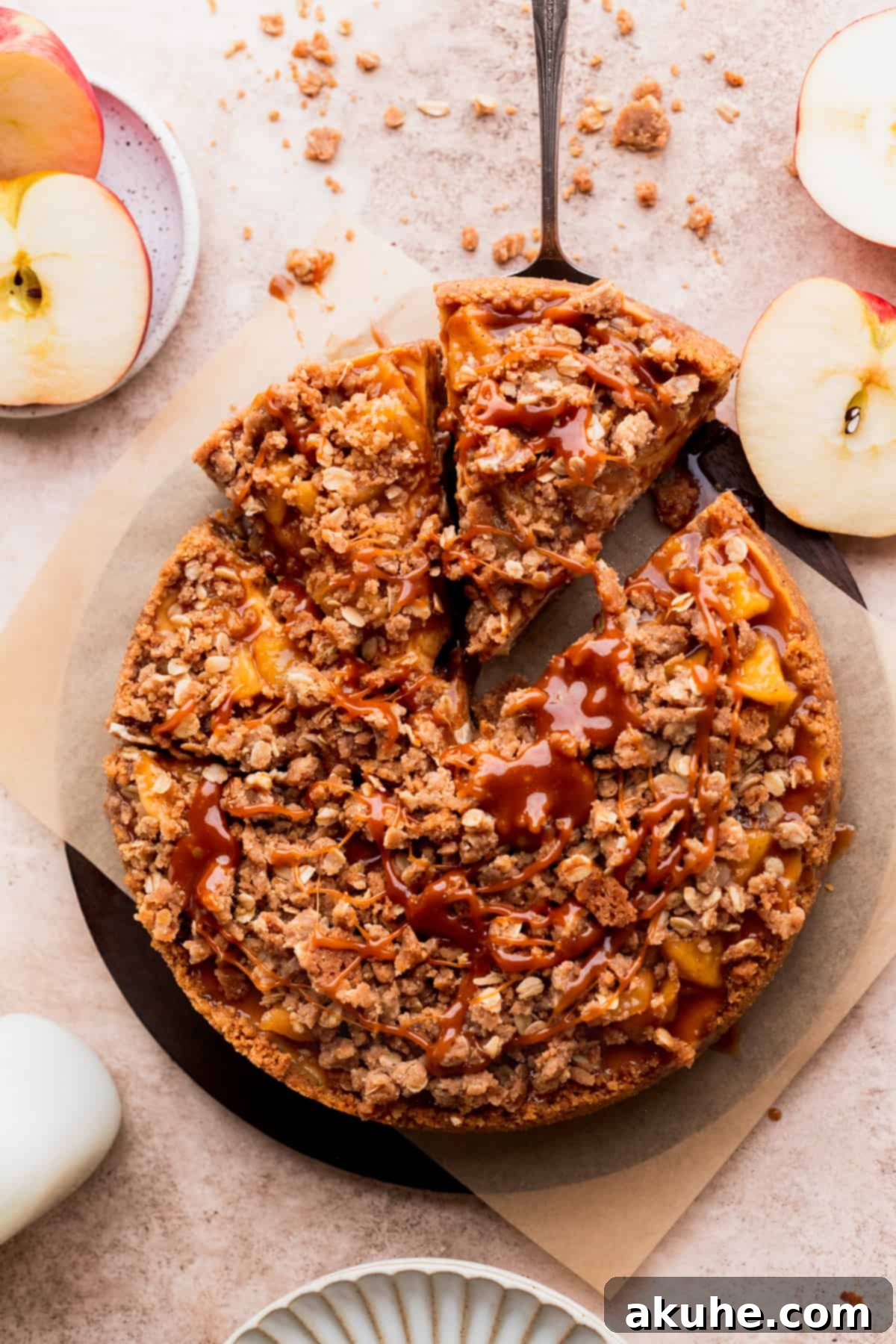 Ultimate Apple Crumble Cheesecake 3 An overhead shot of an apple crumble cheesecake with a slice being removed, showing the layers.