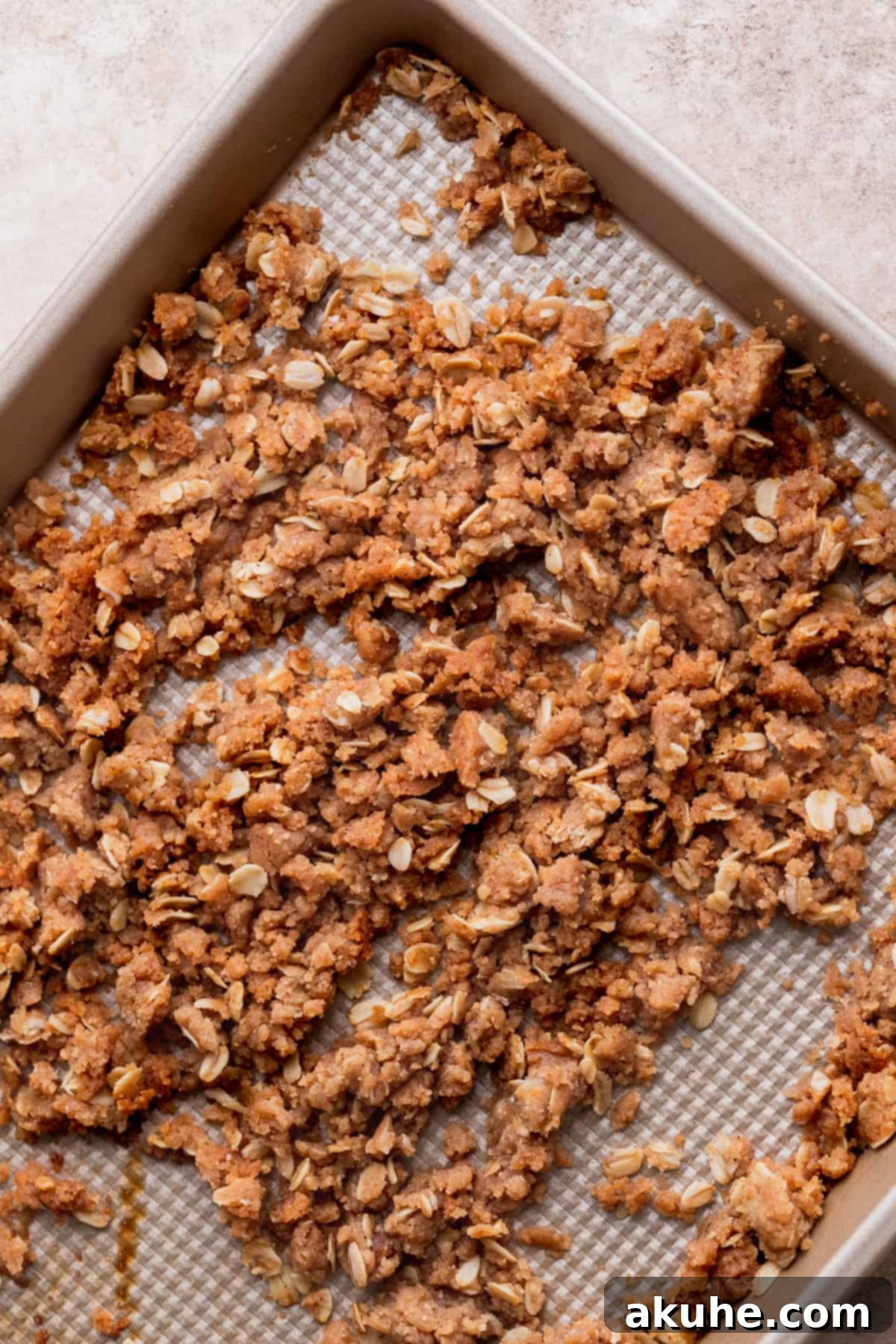 Ultimate Apple Crumble Cheesecake 9 Golden-brown baked cinnamon oat crumble spread on a cookie sheet.