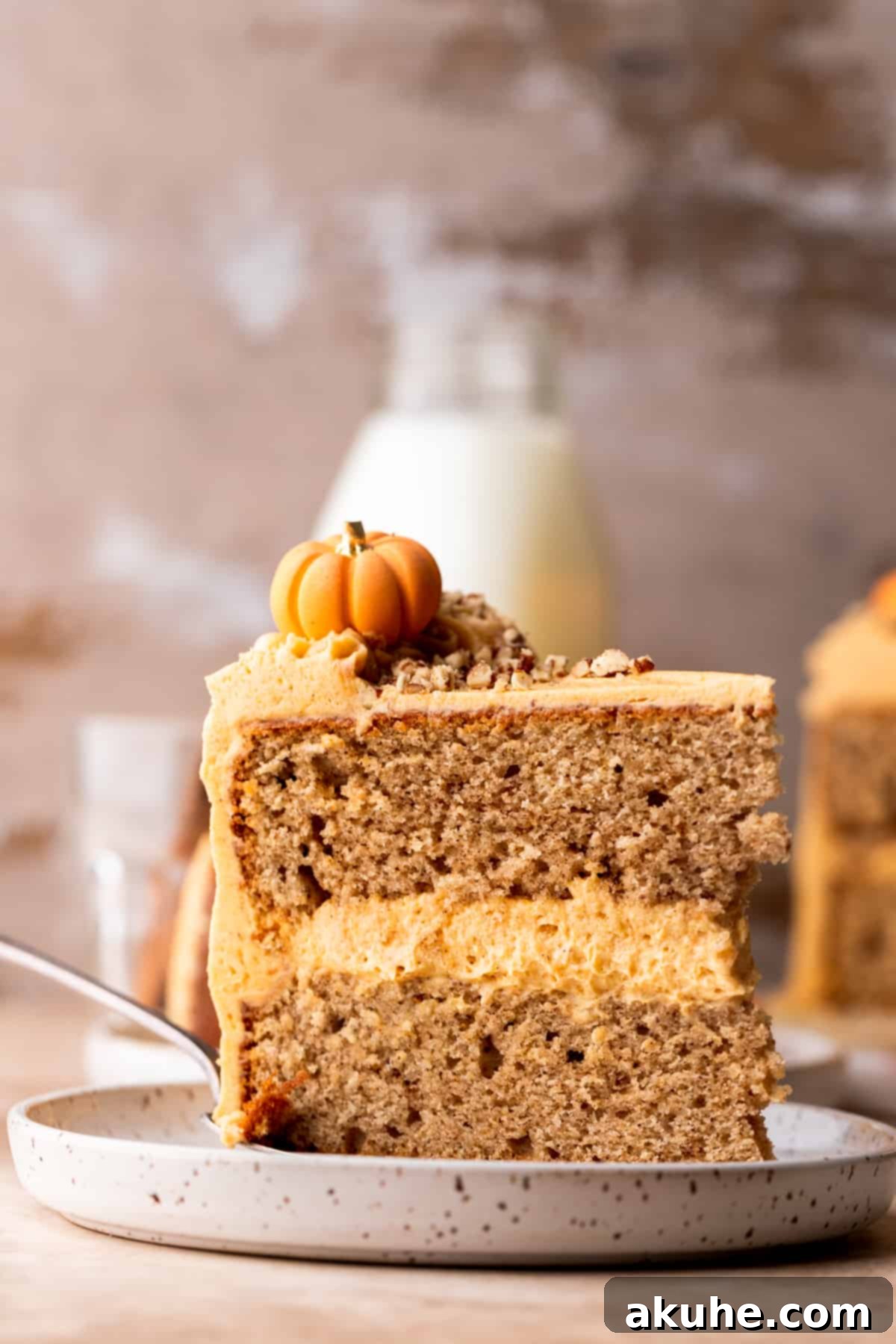 Chai Spiced Cake 2 A single slice of moist chai cake with pumpkin frosting on a white plate, ready to be enjoyed.