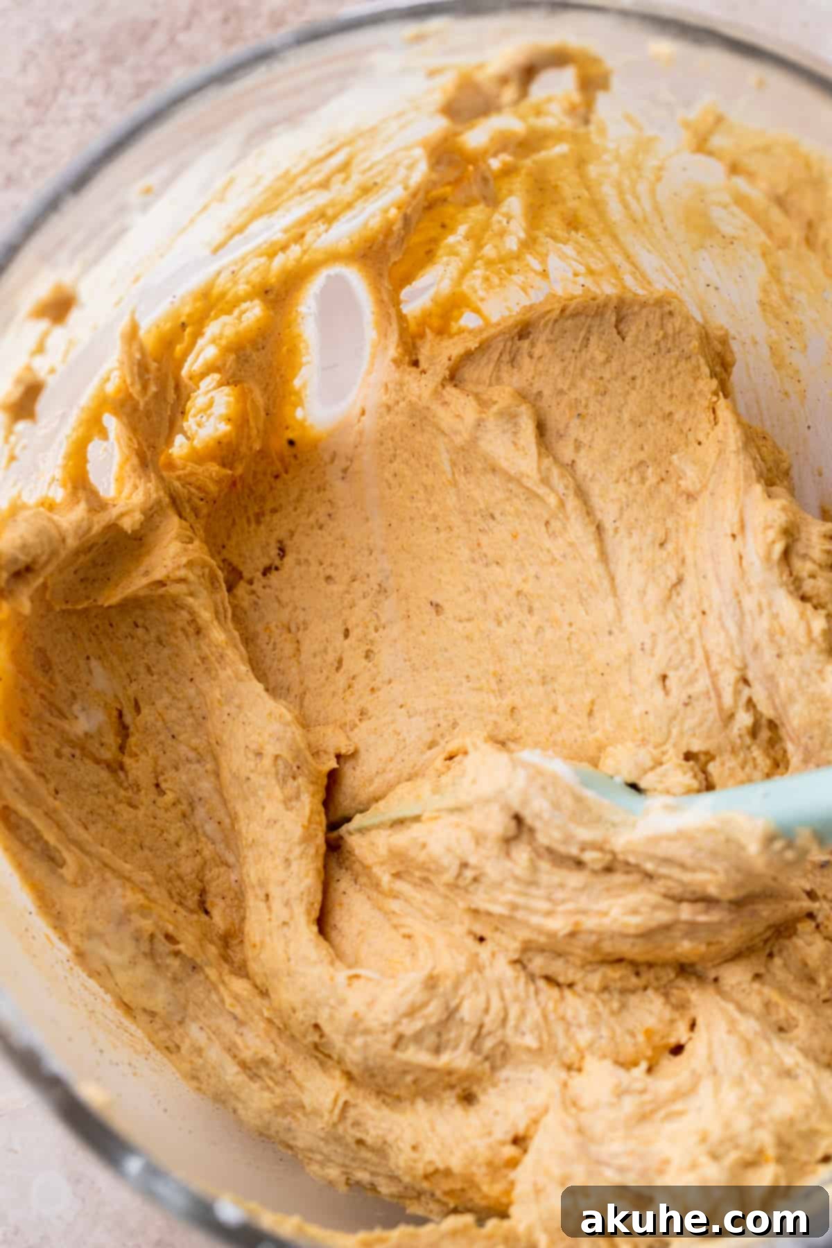 Chai Spiced Cake 7 Creamy, spiced pumpkin frosting in a clear glass mixing bowl.