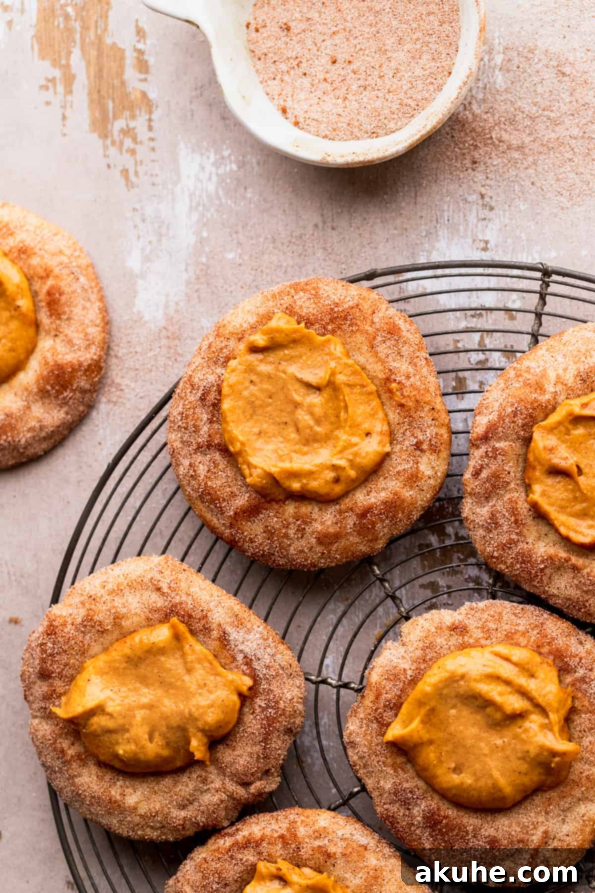 Freshly baked pumpkin pie cookies on a wire cooling rack, generously topped with cinnamon sugar.