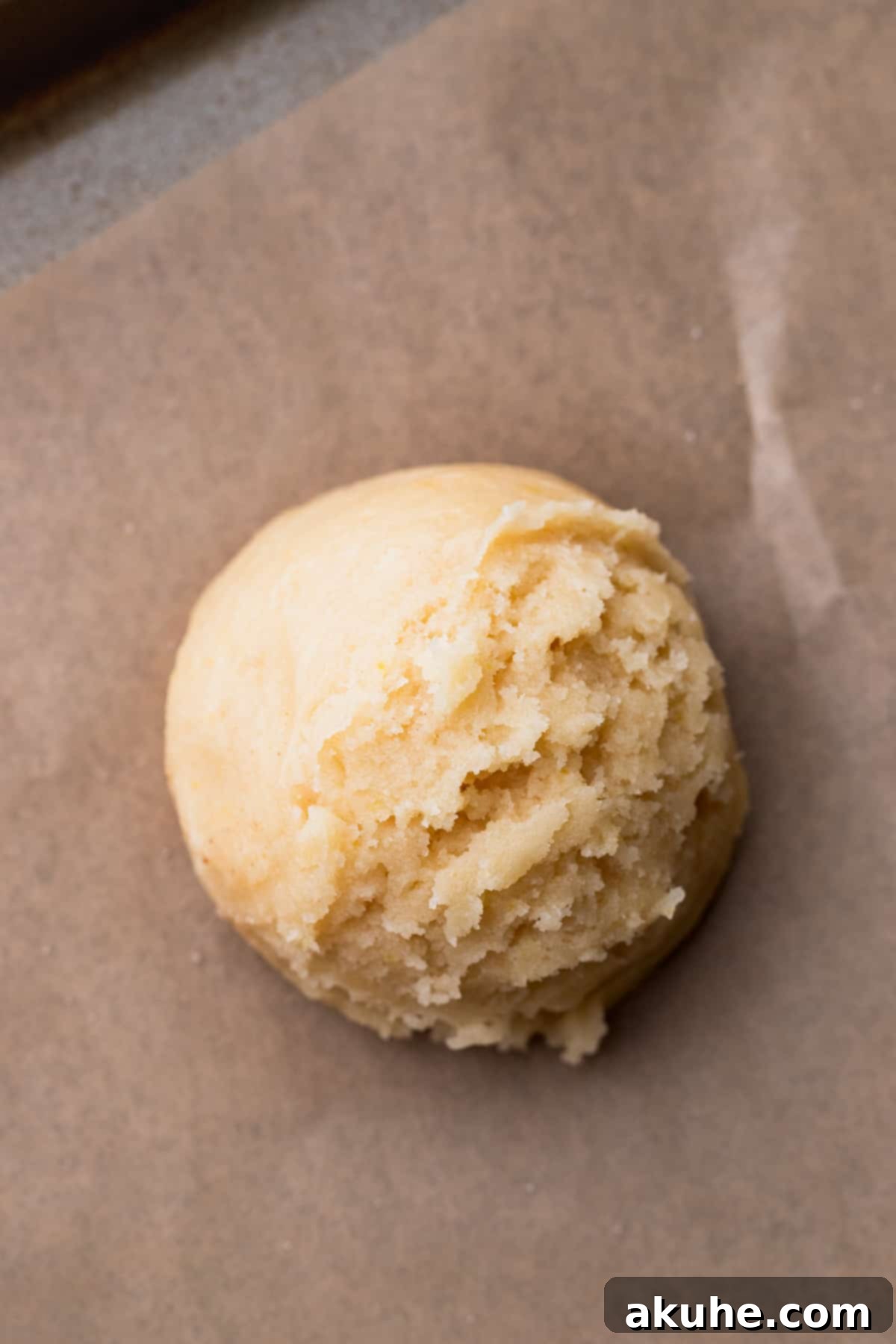 A perfectly rolled cookie dough ball coated in cinnamon sugar, placed on a baking sheet.