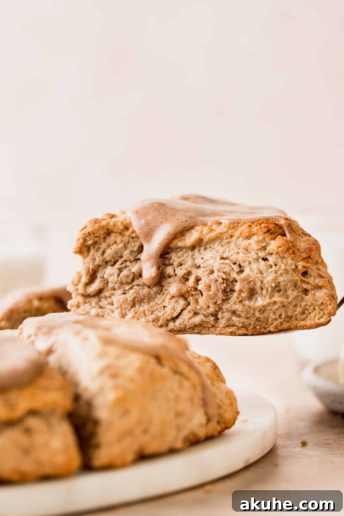 Banana Bread Scones 10 A hand gently taking a cinnamon banana scone from a stack on a marble board.