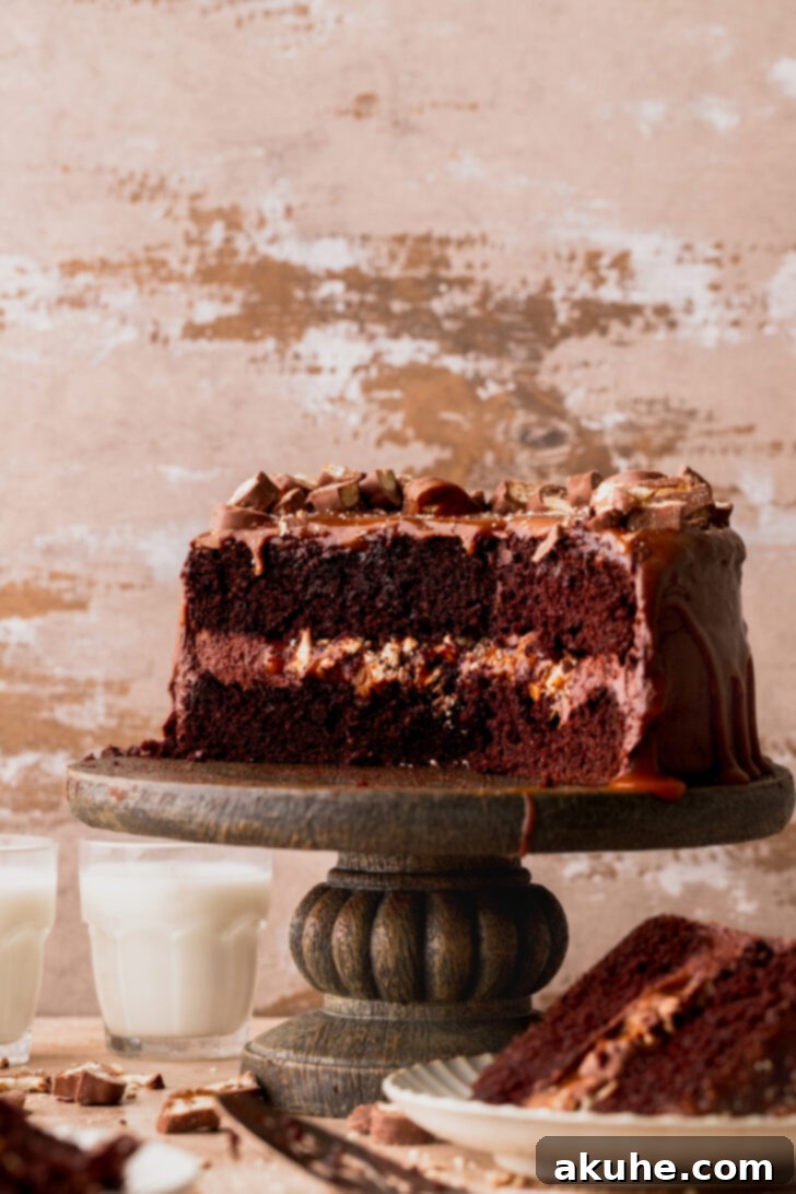 Ultimate Twix Cake 3 Side view of a beautifully decorated multi-layered Twix cake on a cake stand.