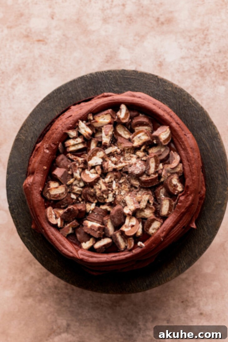 Ultimate Twix Cake 8 Layer of cake with chopped Twix bars on top of caramel.