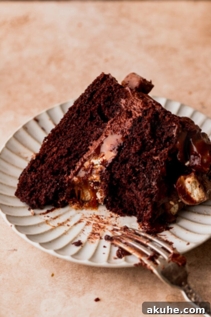 Ultimate Twix Cake 10 Piece of Twix cake on a white plate with a bite taken out, showing the rich layers.