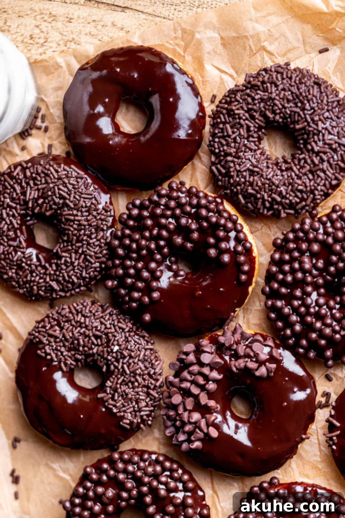 Decadent Chocolate Donut Delights 10 Beautifully arranged chocolate glazed donuts on parchment paper, ready to be served or stored.