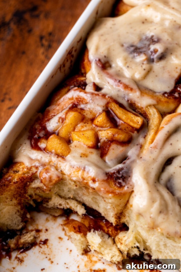 Homemade Apple Cinnamon Rolls 3 A baking pan filled with golden-brown apple cinnamon rolls, fresh from the oven, glistening with icing.