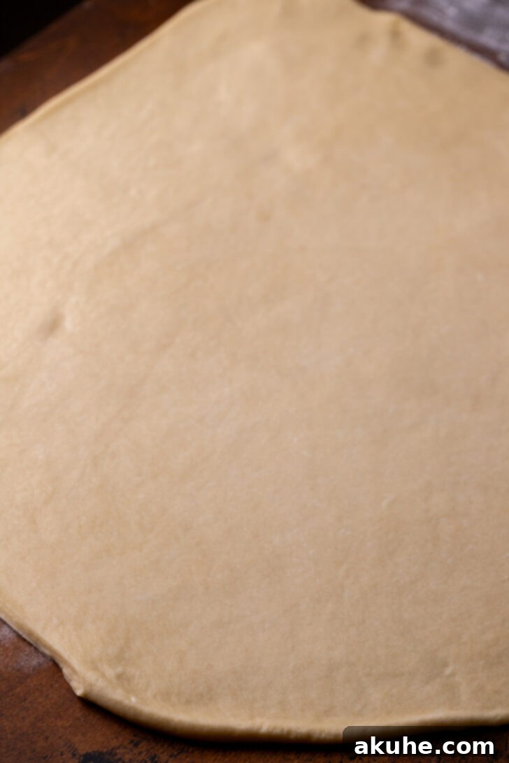 Homemade Apple Cinnamon Rolls 4 Freshly rolled out dough on a wooden board, shaped into a perfect rectangle, ready for filling.