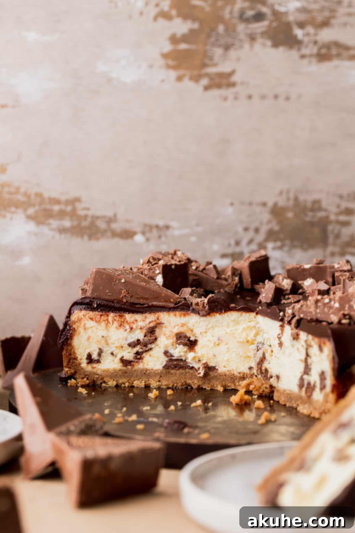 Decadent Toblerone Cheesecake 11 Fully decorated Toblerone cheesecake on a wood board, garnished with chocolate ganache and Toblerone pieces.