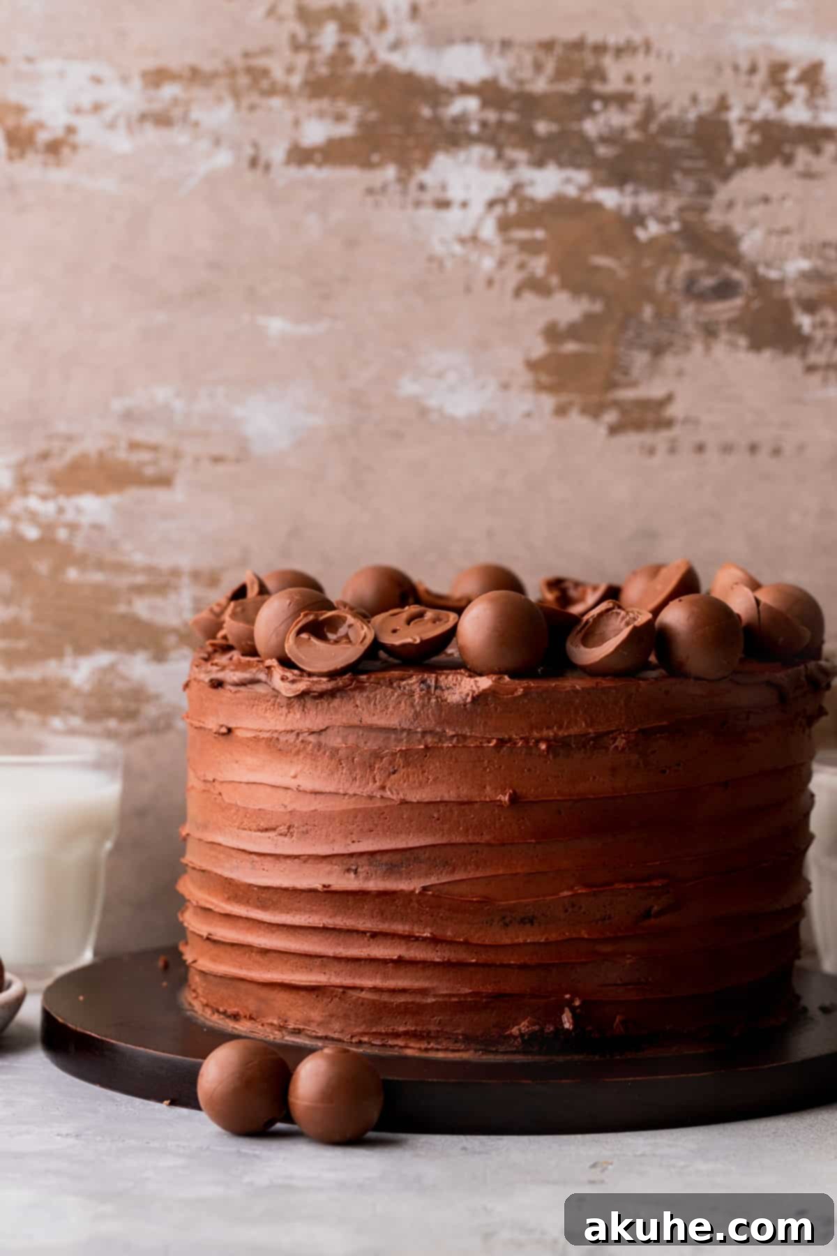 A beautifully decorated chocolate truffle cake sitting on a rustic wood board, adorned with whole truffles and ready to be sliced.