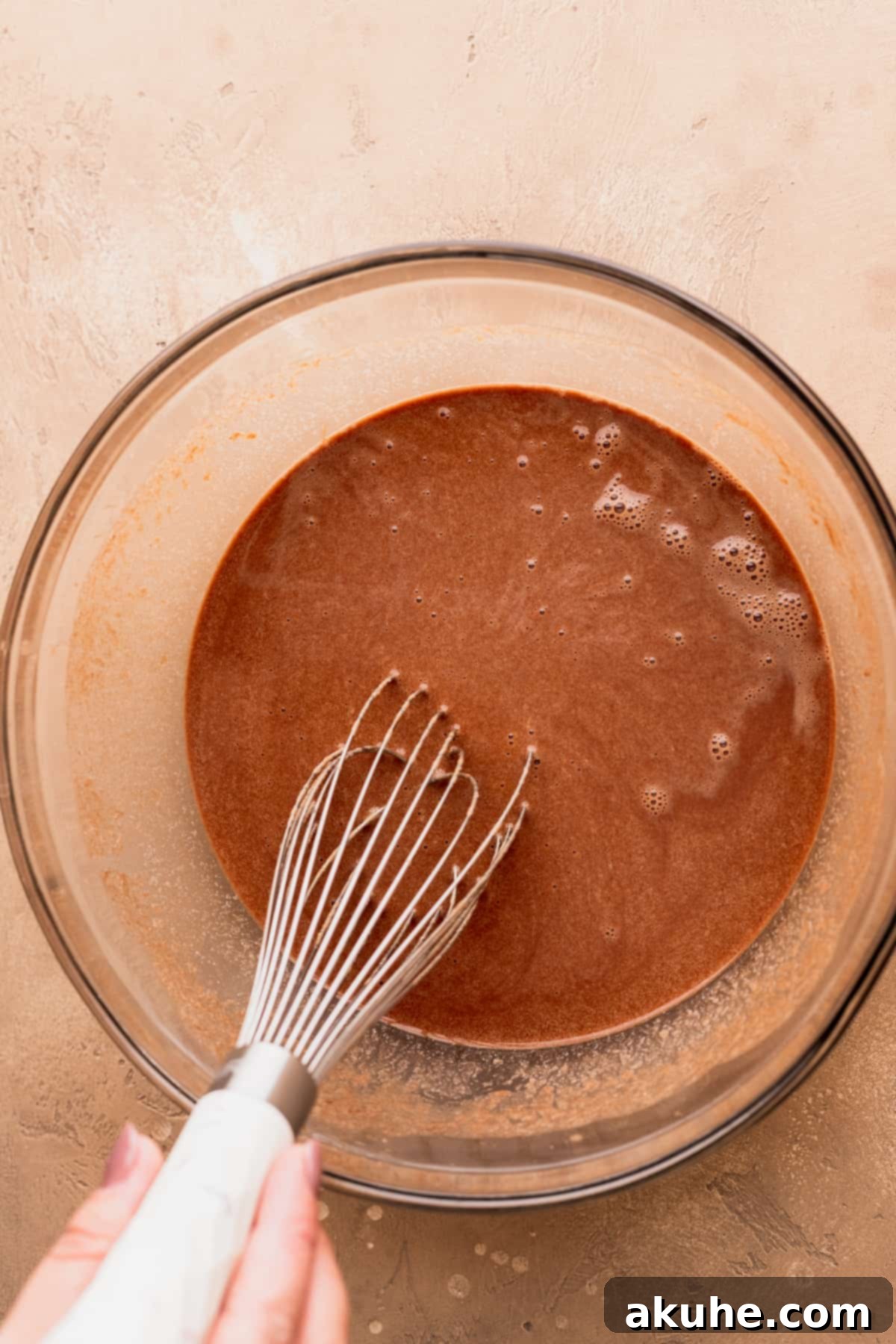 Wet ingredients expertly mixed in a large bowl, showing a smooth, rich brown liquid, ready for the dry components.