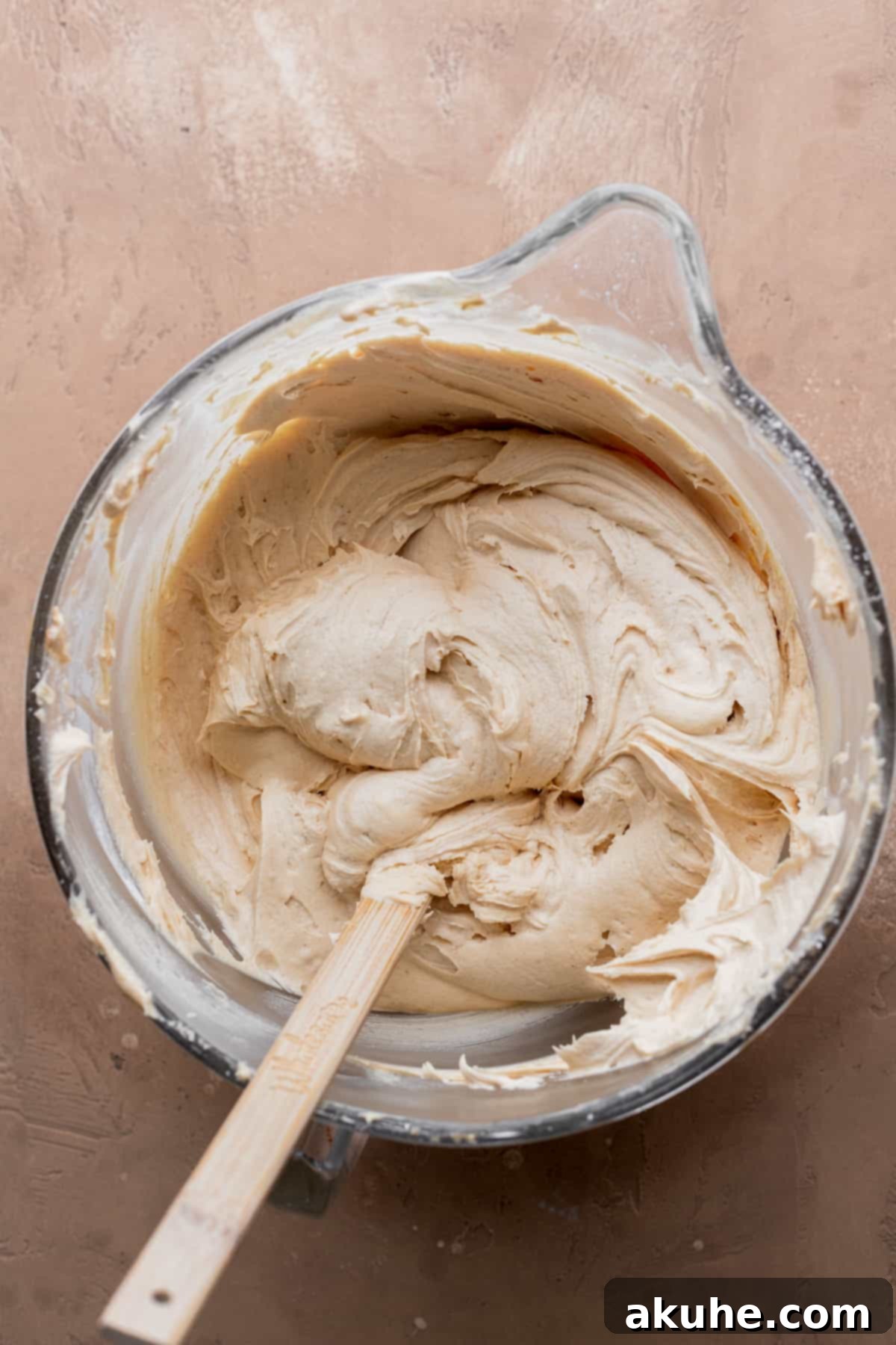 Decadent Peanut Butter Chocolate Cake 7 Smooth and creamy peanut butter frosting in a clear glass bowl, ready for cake assembly.