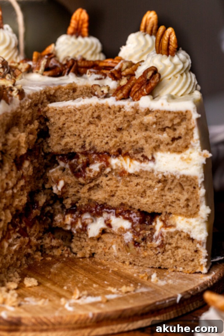A delectable slice of Pecan Pie Cake being carefully removed from the full cake, showcasing its beautiful layers of spice cake and gooey pecan filling, topped with a generous swirl of cream cheese frosting.
