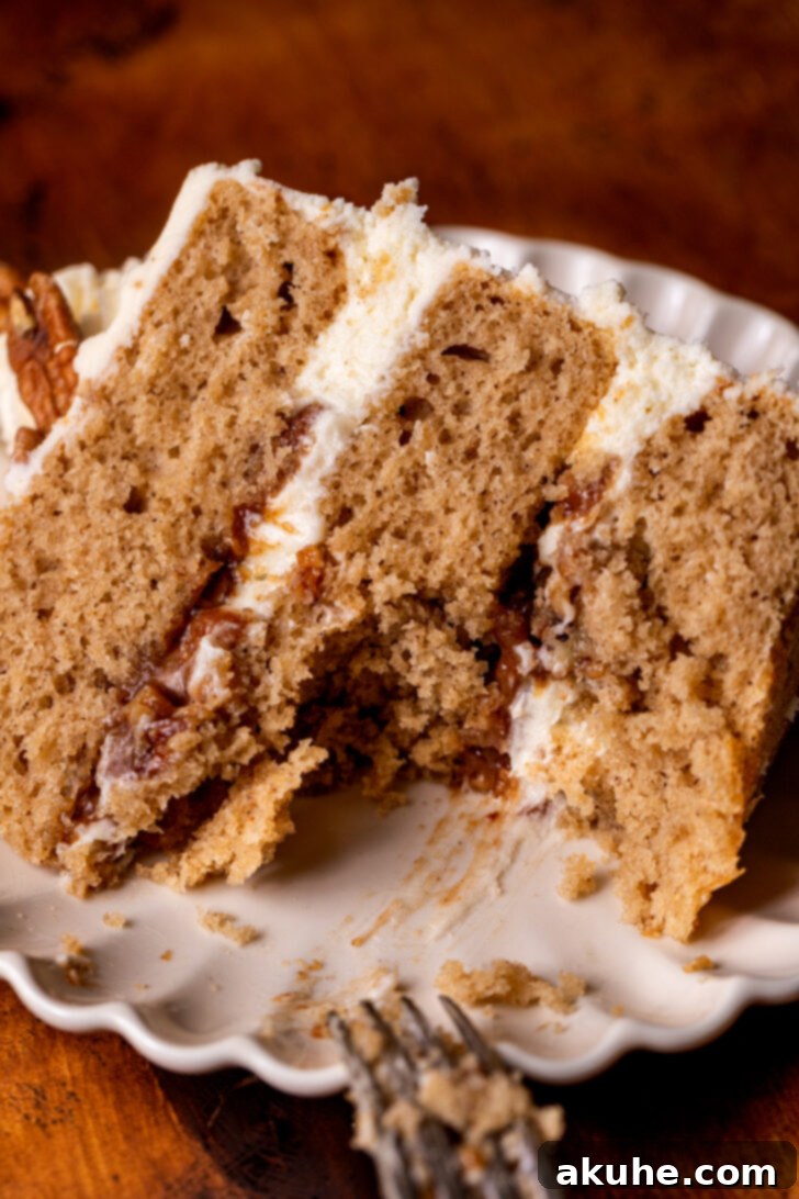 A delicious slice of Pecan Pie Cake with a bite taken out, showing the moist cake, rich filling, and creamy frosting.