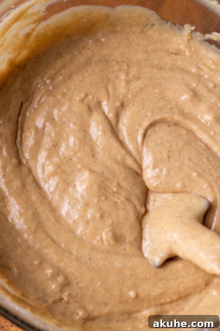 A bowl filled with light brown spice cake batter, ready for baking.