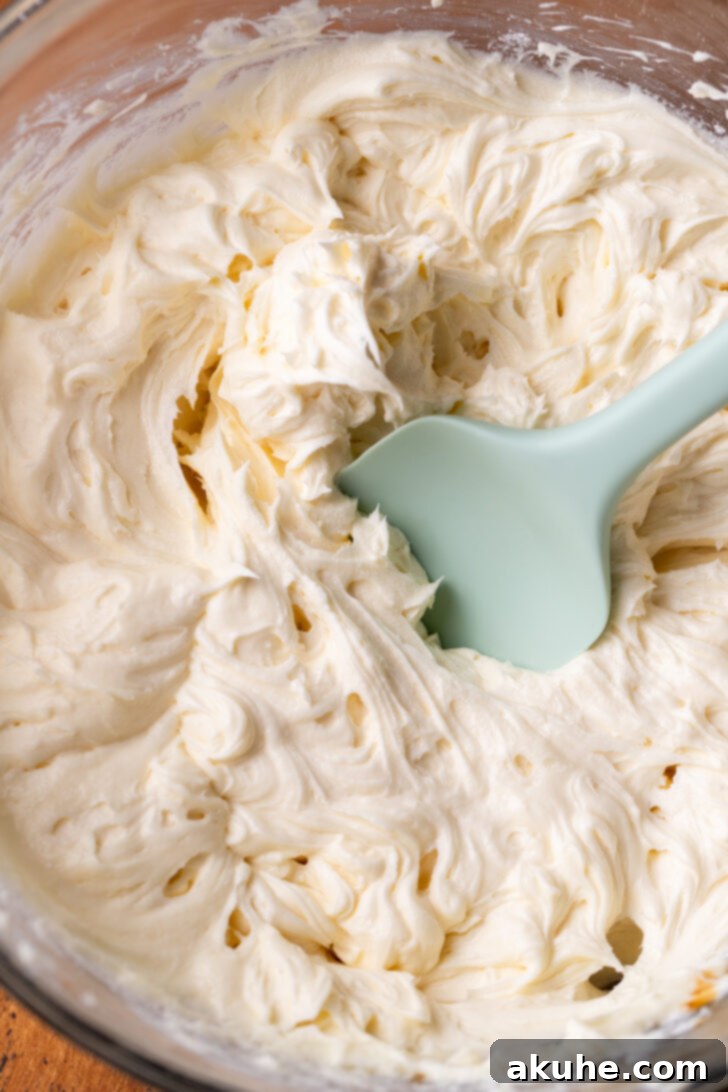 A mixing bowl filled with fluffy white cream cheese frosting.