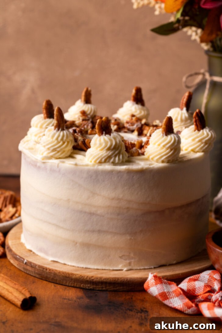 A beautifully decorated Pecan Pie Cake sitting on a wooden serving board, adorned with piped frosting dollops and whole pecans.