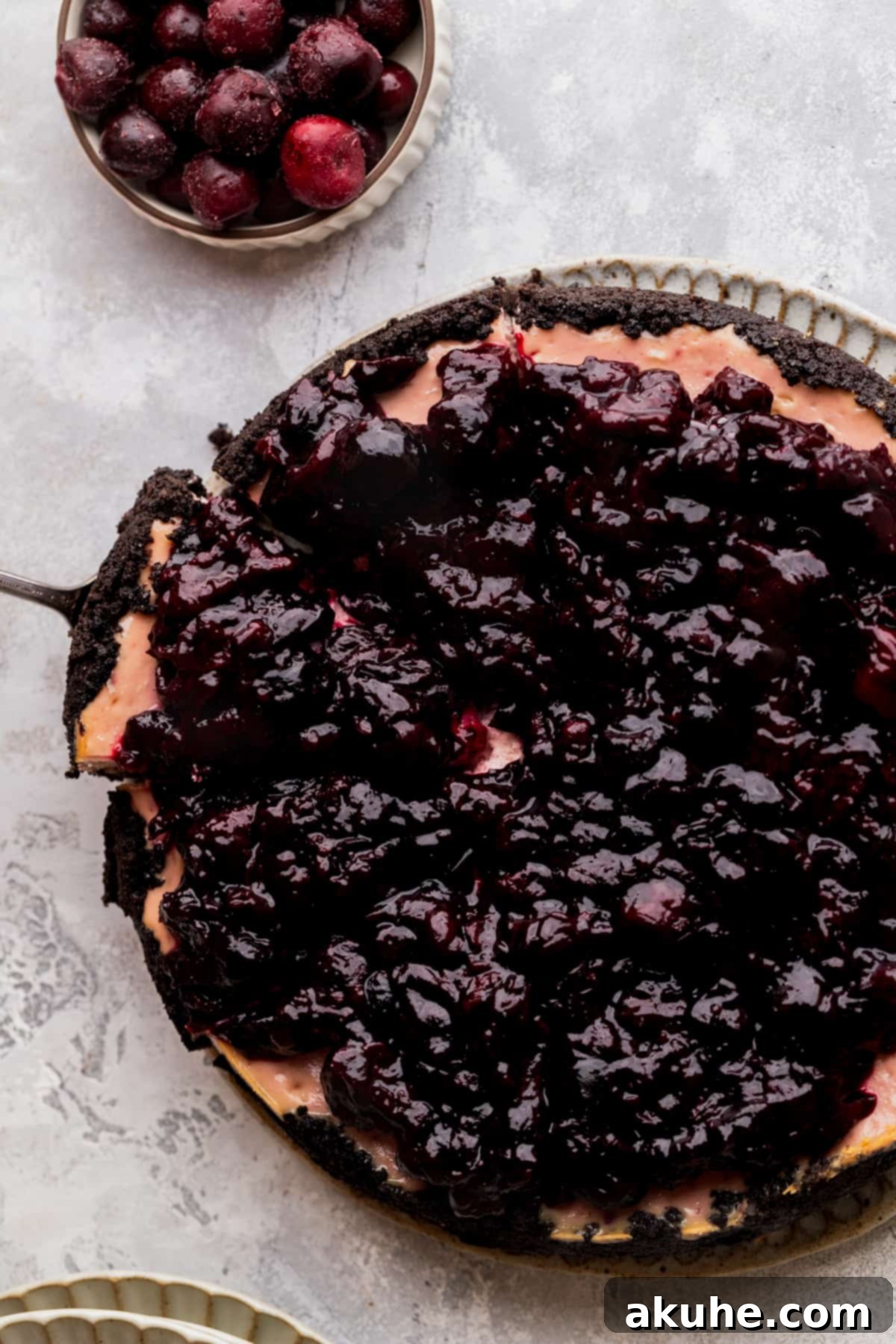 Decadent Cherry Cheesecake 3 Cherry cheesecake on a platter with a slice being taken out.