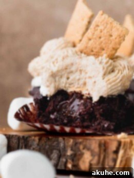 A bite missing from s'mores cupcakes on a wooden board.