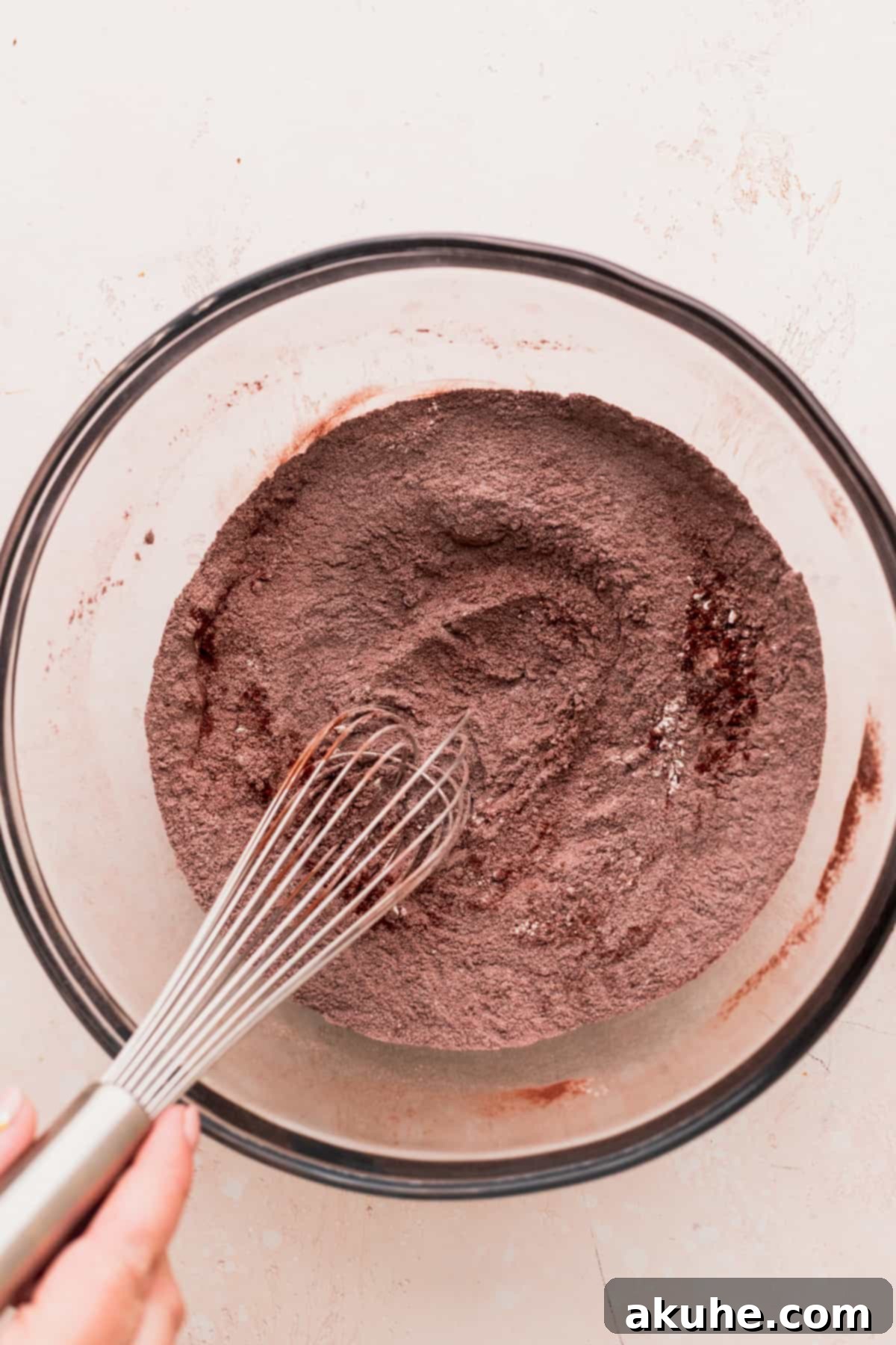 Dry ingredients, including flour and cocoa powder, meticulously measured and ready in a glass bowl.