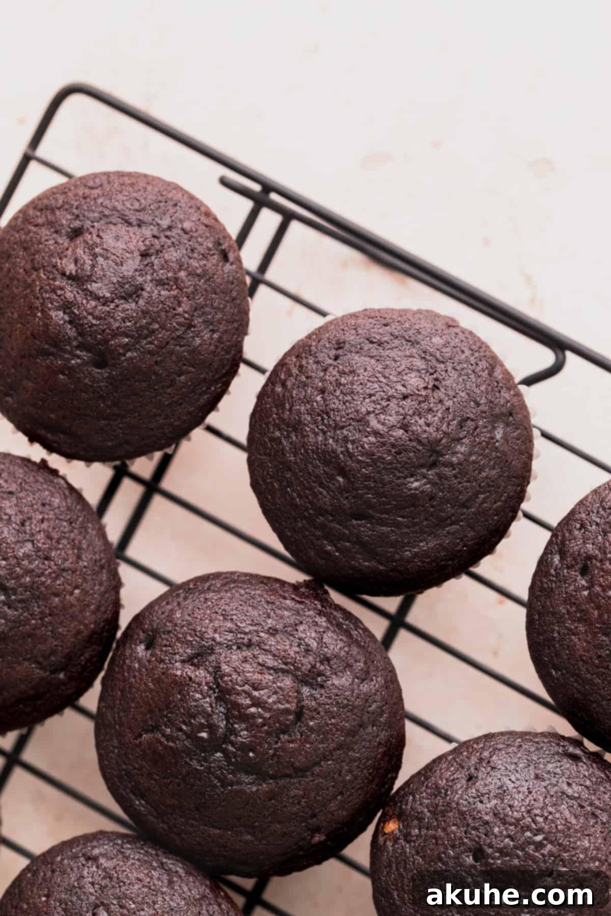 Freshly baked chocolate cupcakes cooling on a wire rack after being removed from the oven.