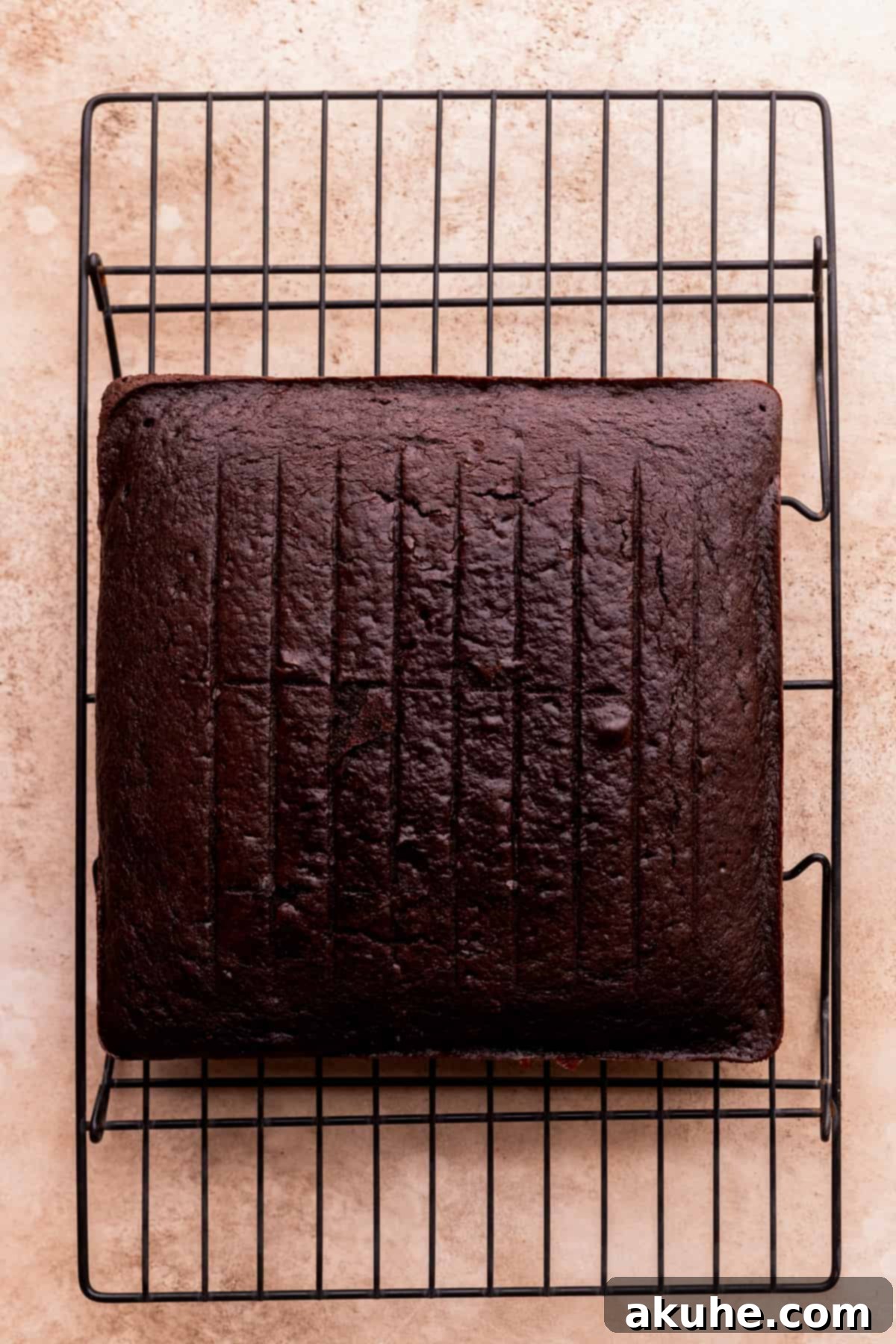 Velvet Chocolate Ganache Torte 6 A freshly baked square chocolate cake cooling on a wire rack after being removed from the oven.