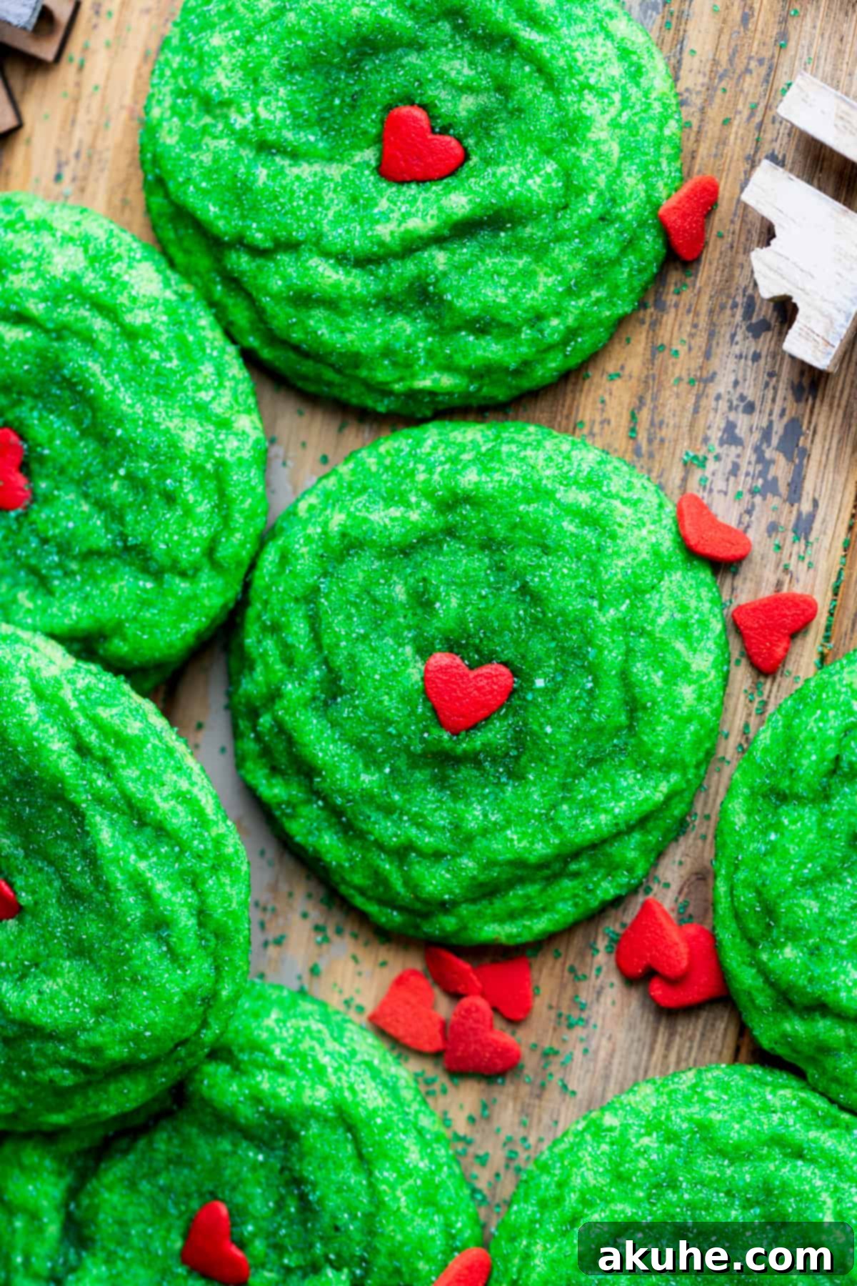 Vibrant green Grinch cookies adorned with jumbo red heart sprinkles, ready for the holidays.
