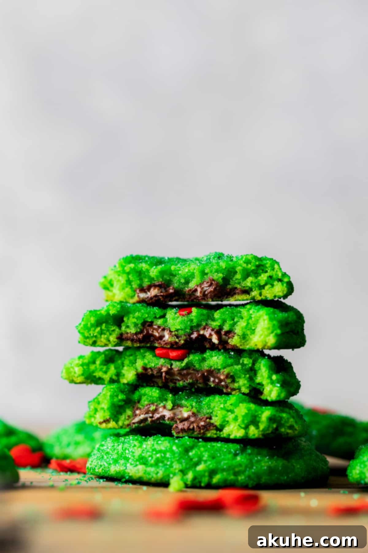 Stack of green Grinch cookies, one split open to reveal the gooey melted Andes mint filling inside.