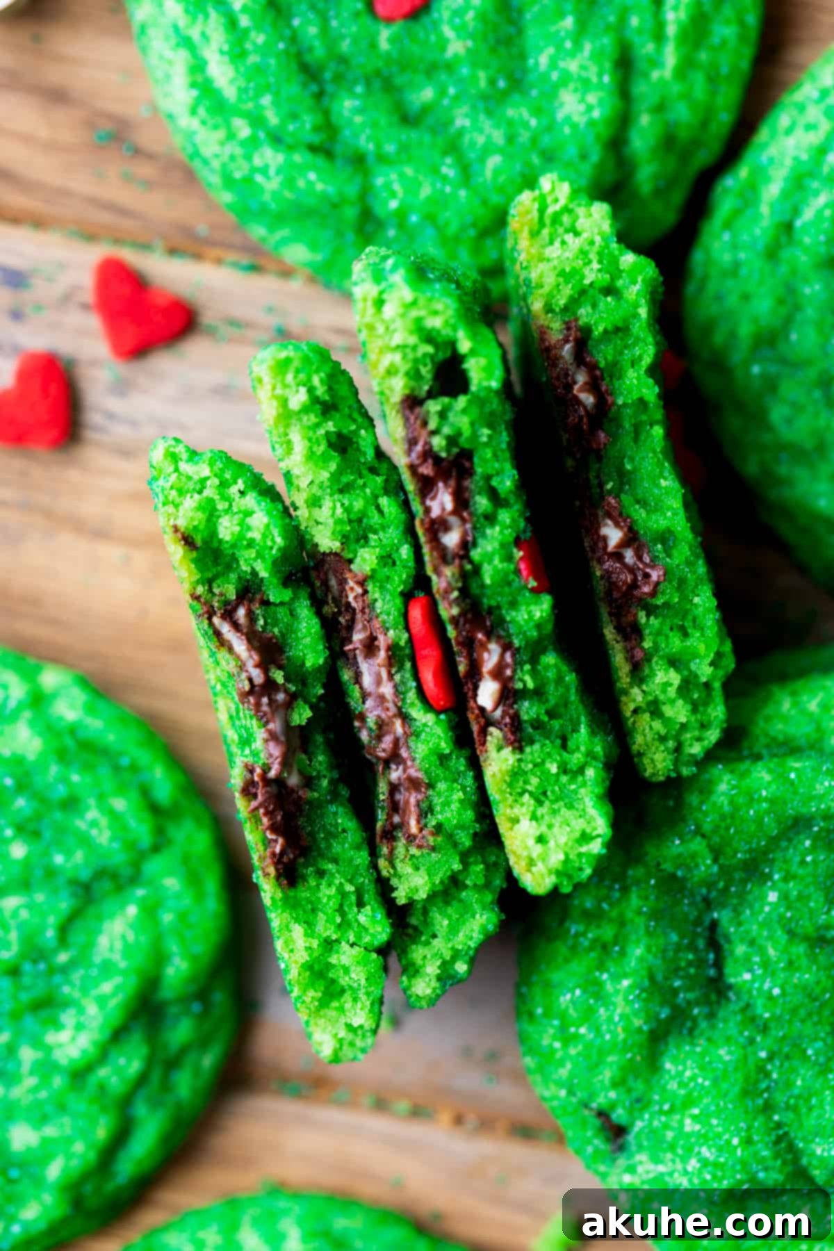 Two vibrant green Grinch cookies, split in half to reveal their luscious melted mint chocolate centers.