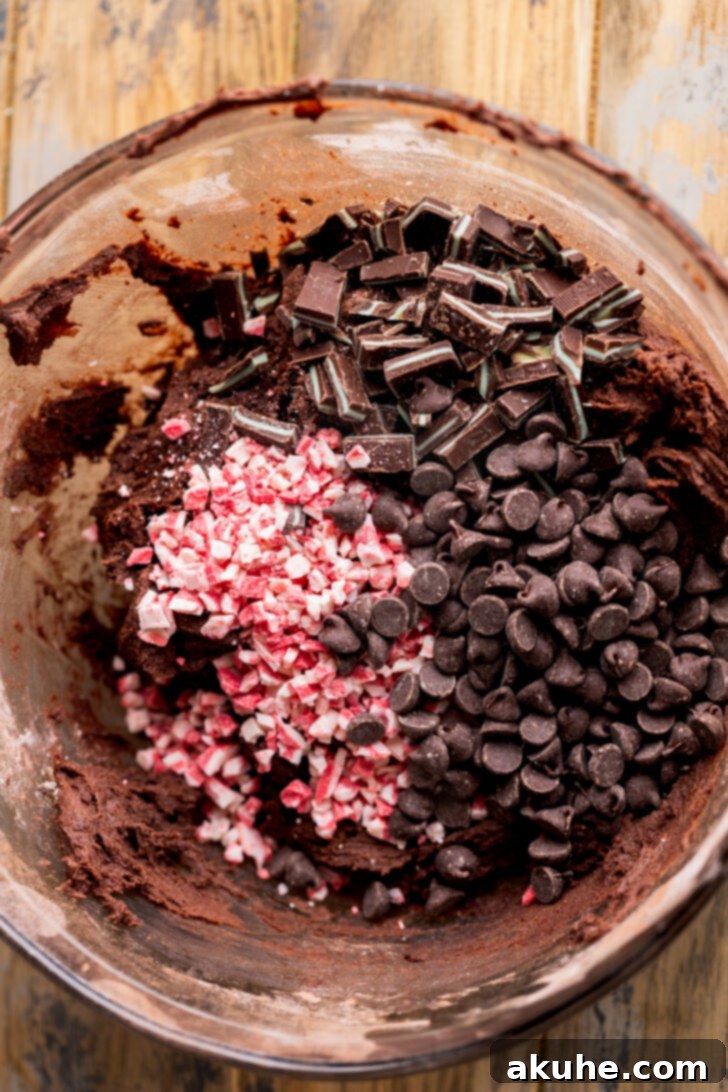 Chopped Andes mints, peppermint chips, and chocolate chips resting on top of cookie dough.